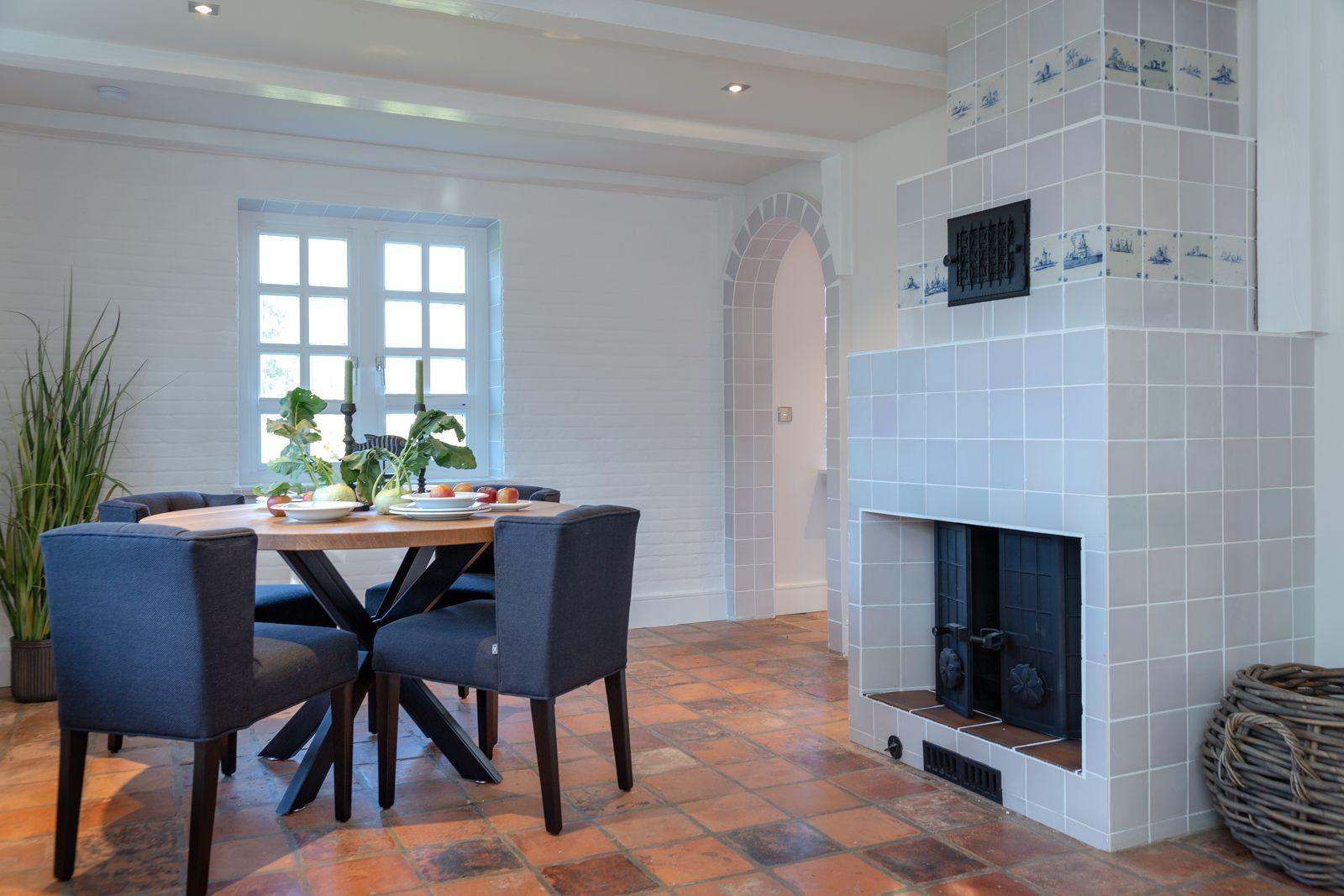 Dining room with table, chairs, and tiled fireplace on the wall.