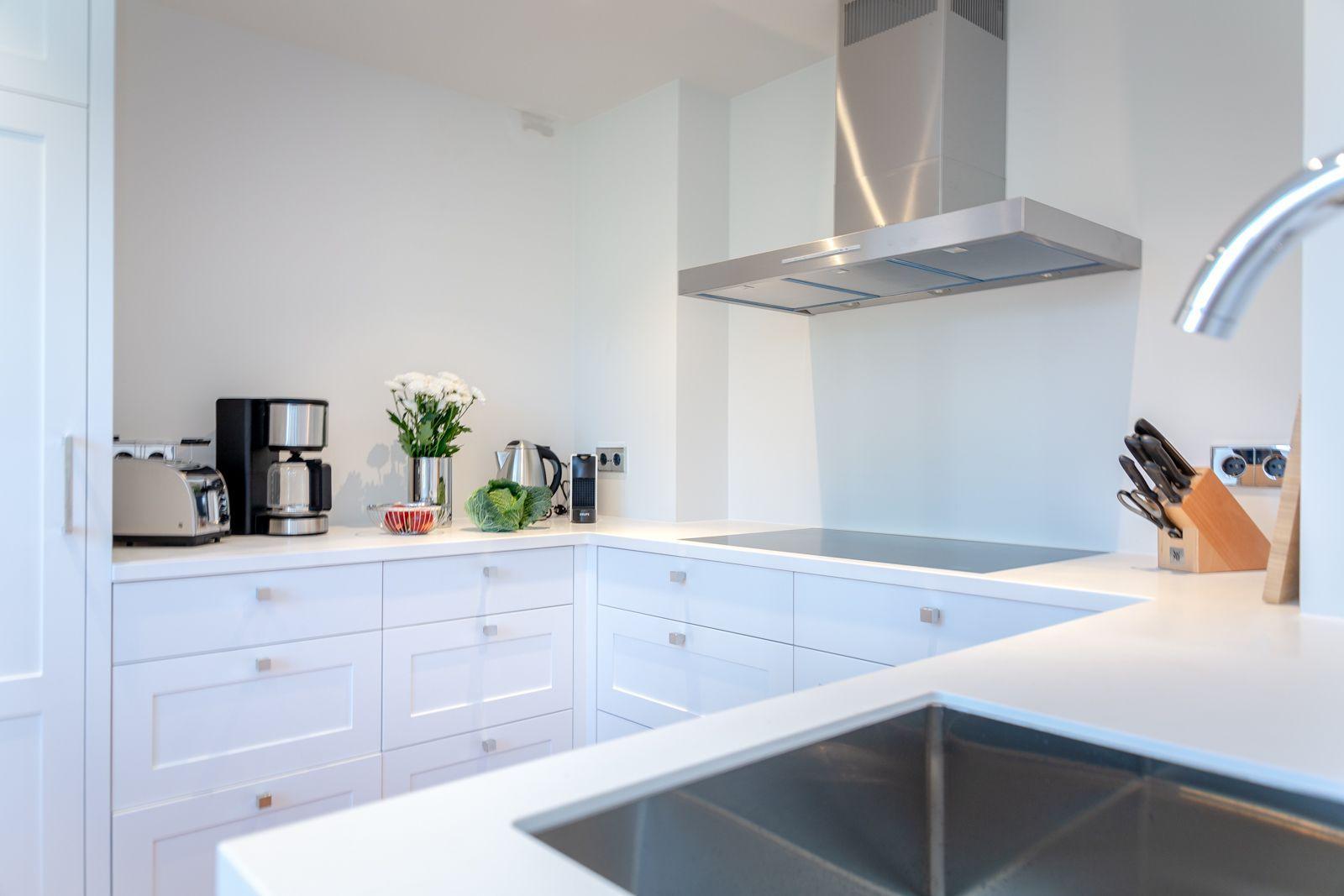 Modern kitchen with white cabinets, stainless steel stove, and countertop.