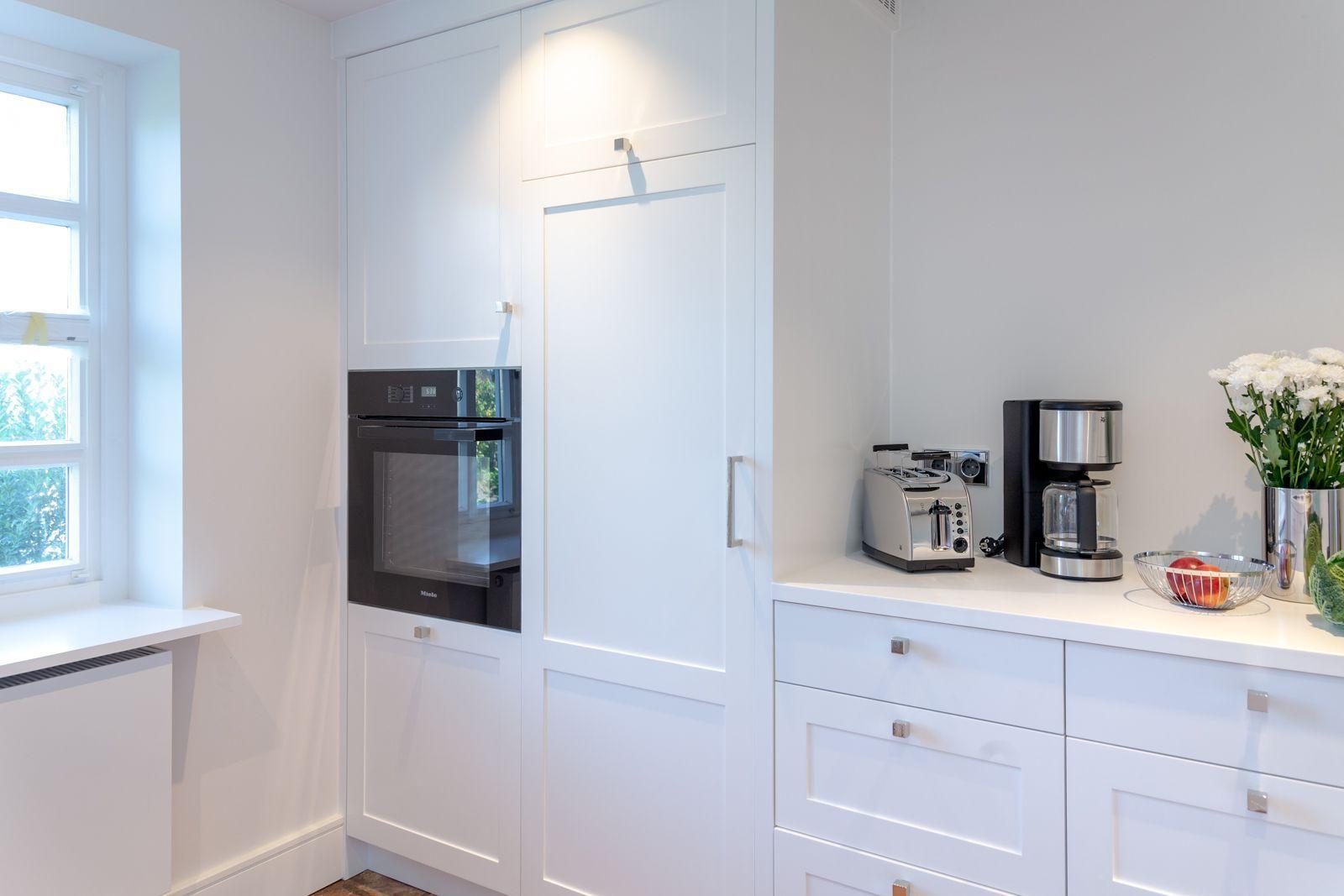 Kitchen with white cabinets, built-in oven, and countertop with coffee maker and toaster.
