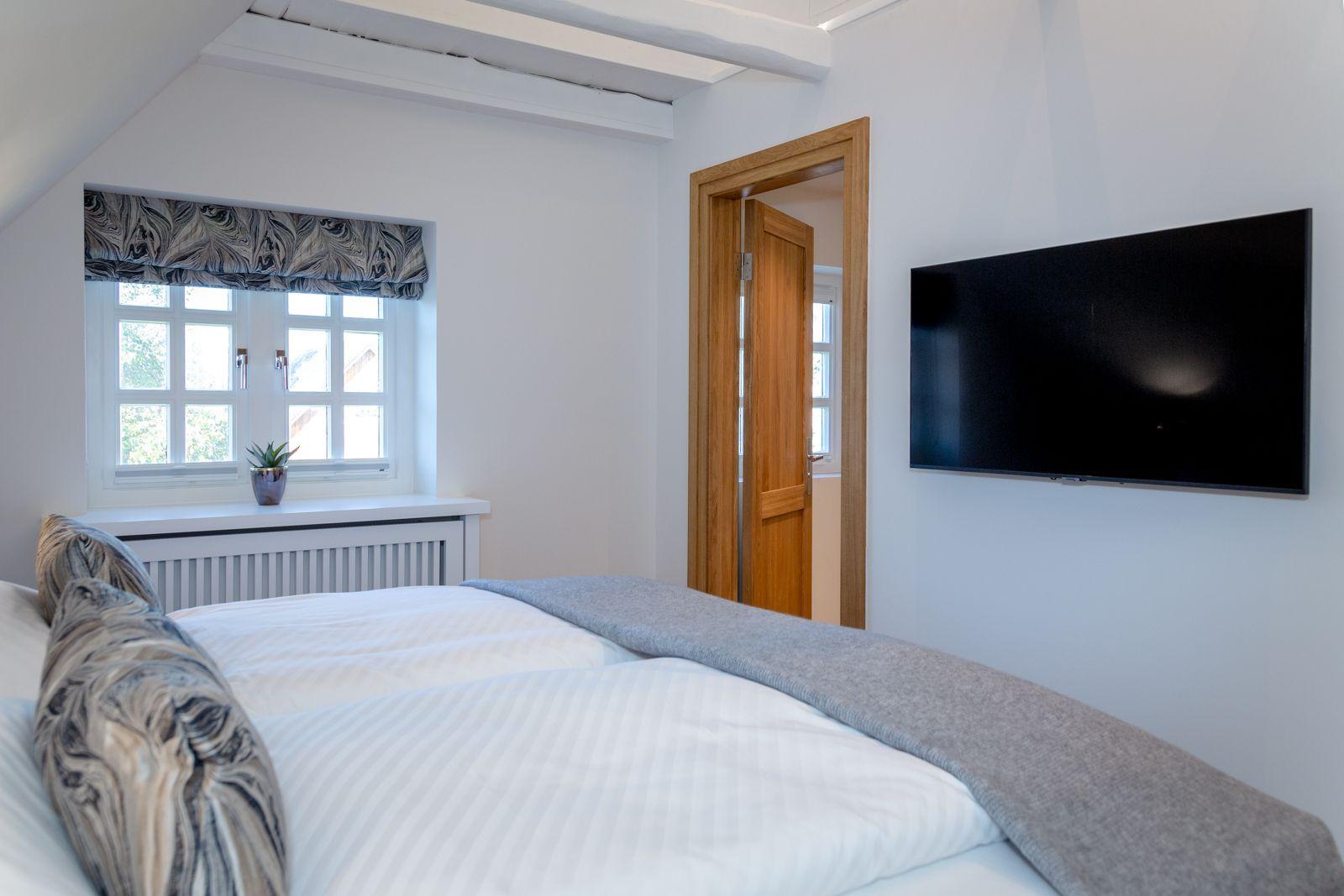Bedroom with bed, window, and wall-mounted TV