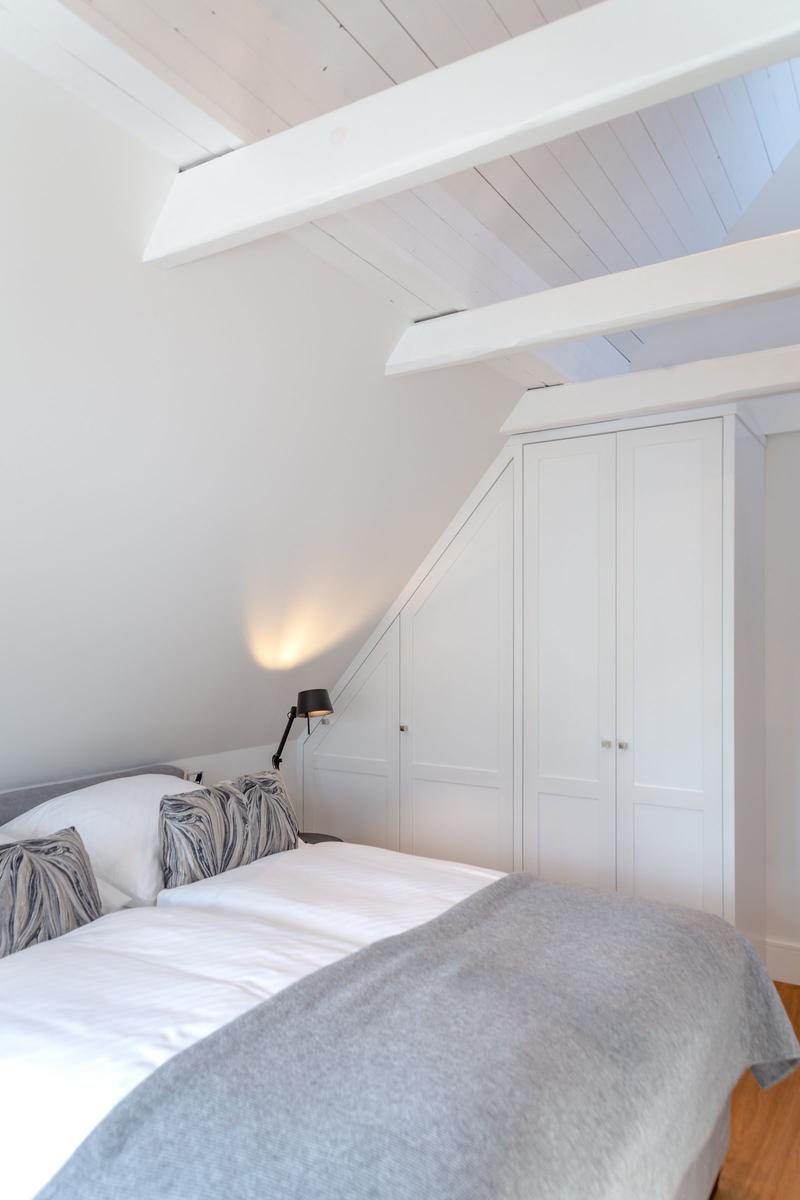 Bedroom with double bed, white wardrobes, and wooden beams on the ceiling.