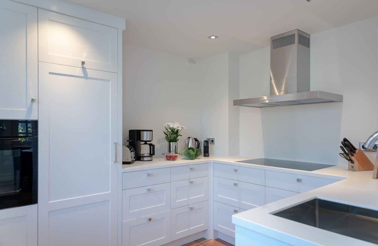 White kitchen with stainless steel stove and countertop.