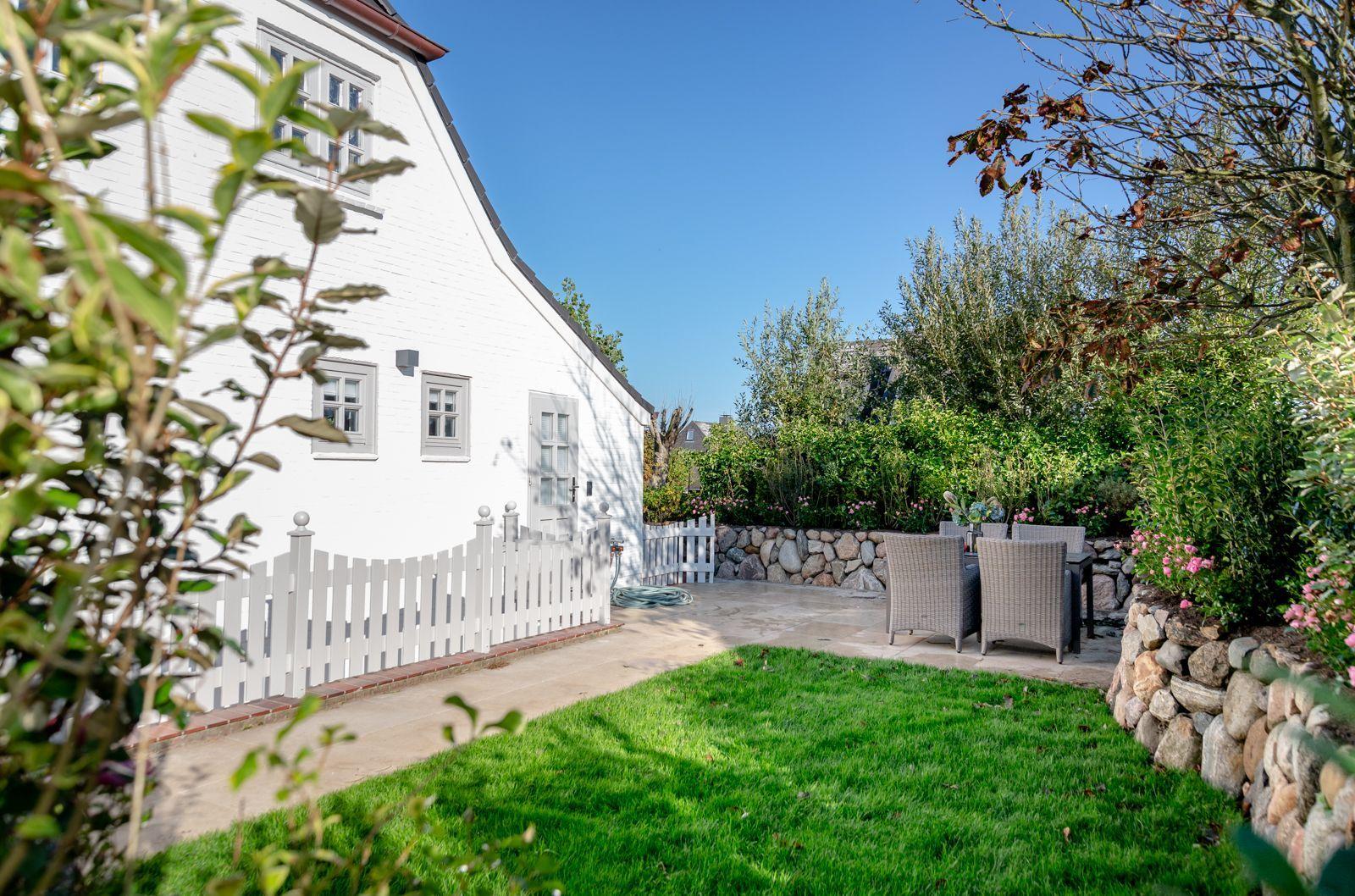White villa with garden, terrace, and garden furniture.