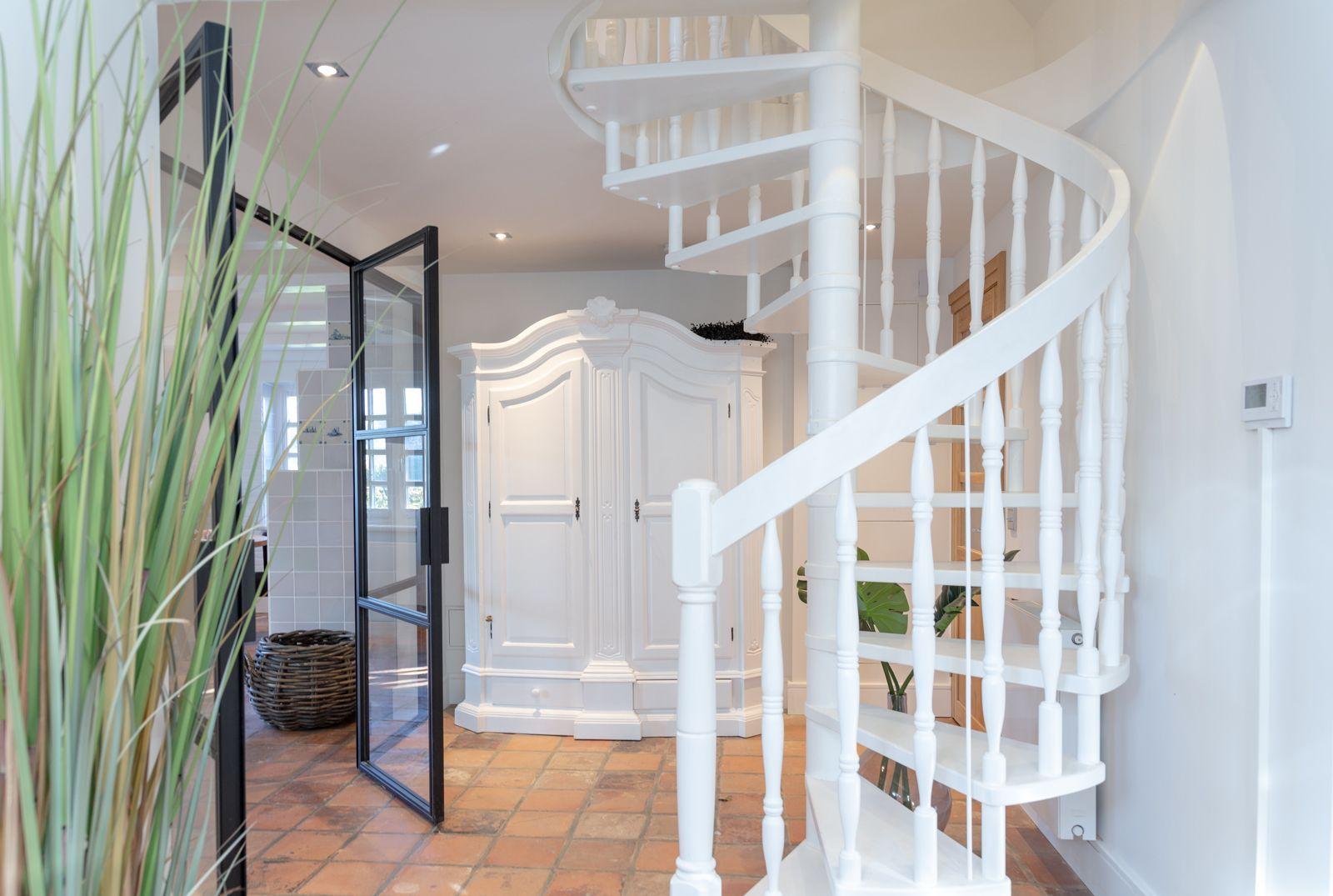 White spiral staircase, large wardrobe and terracotta floor in entrance area