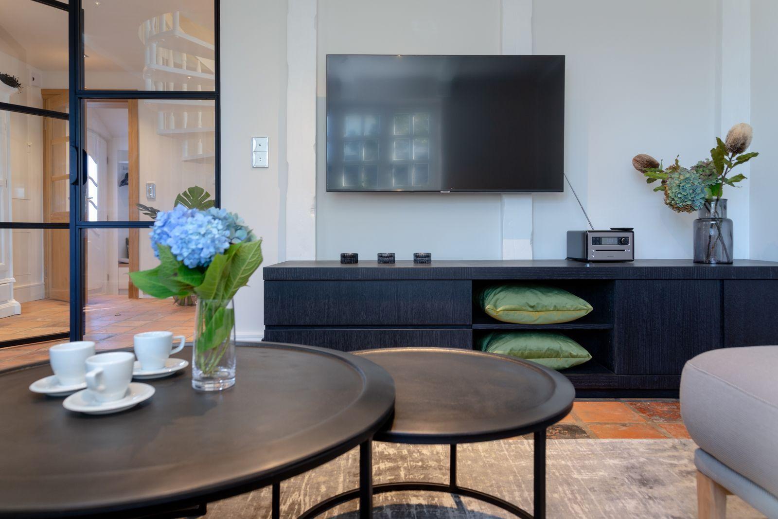Living room with TV, coffee table, and floral arrangement.