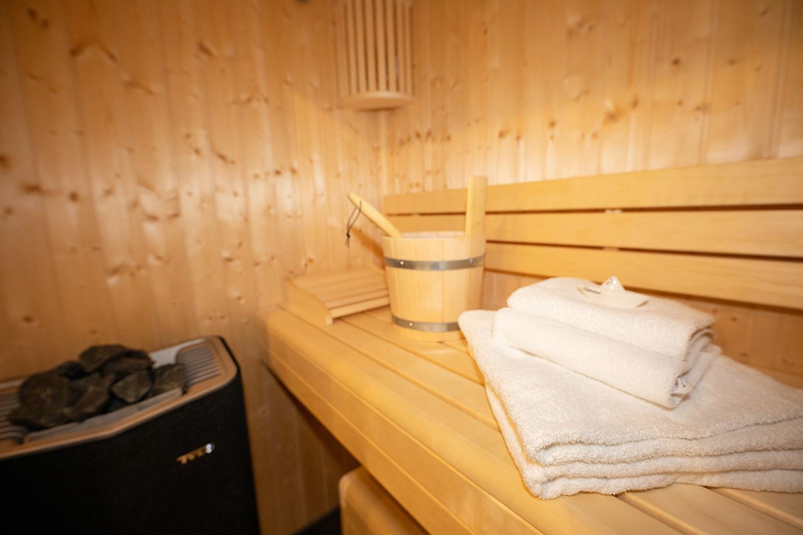 Sauna mit Holzbank, gefalteten Handtüchern und Holzwaschkanister.