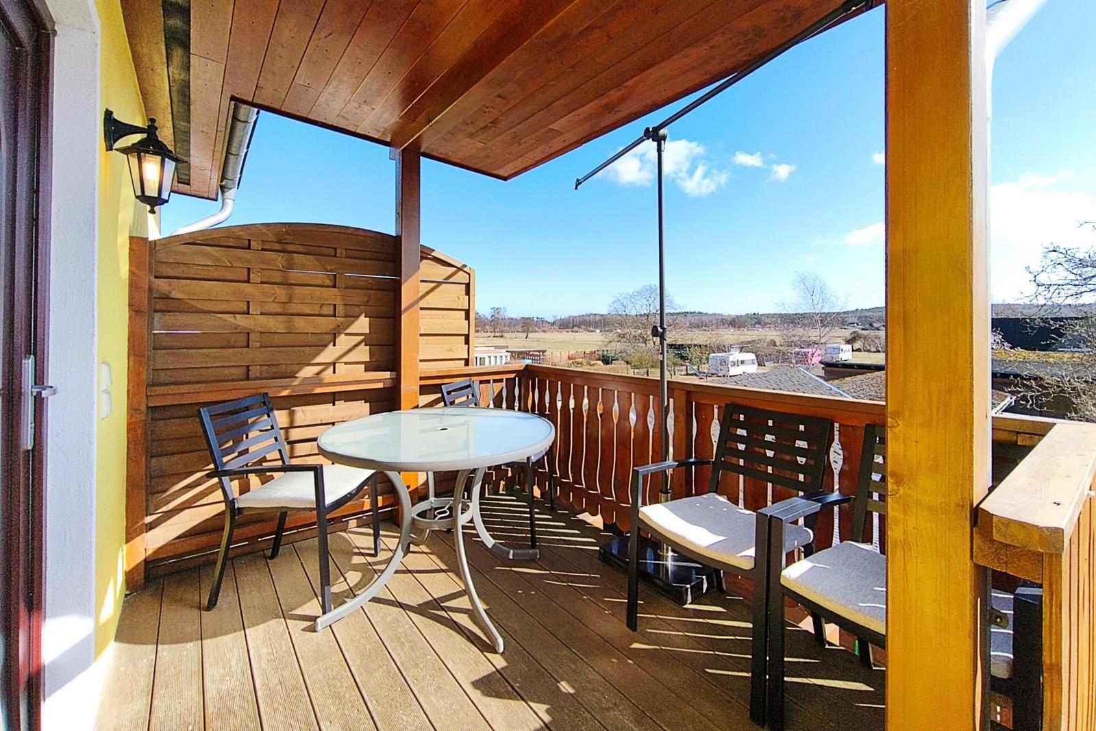 Sonniger Balkon mit Sitzmöbeln und weitem Blick über Loddin