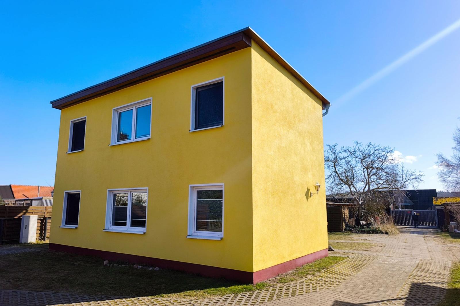 Seitenansicht der Unterkunft mit Zugangsbereich und Stellplatz