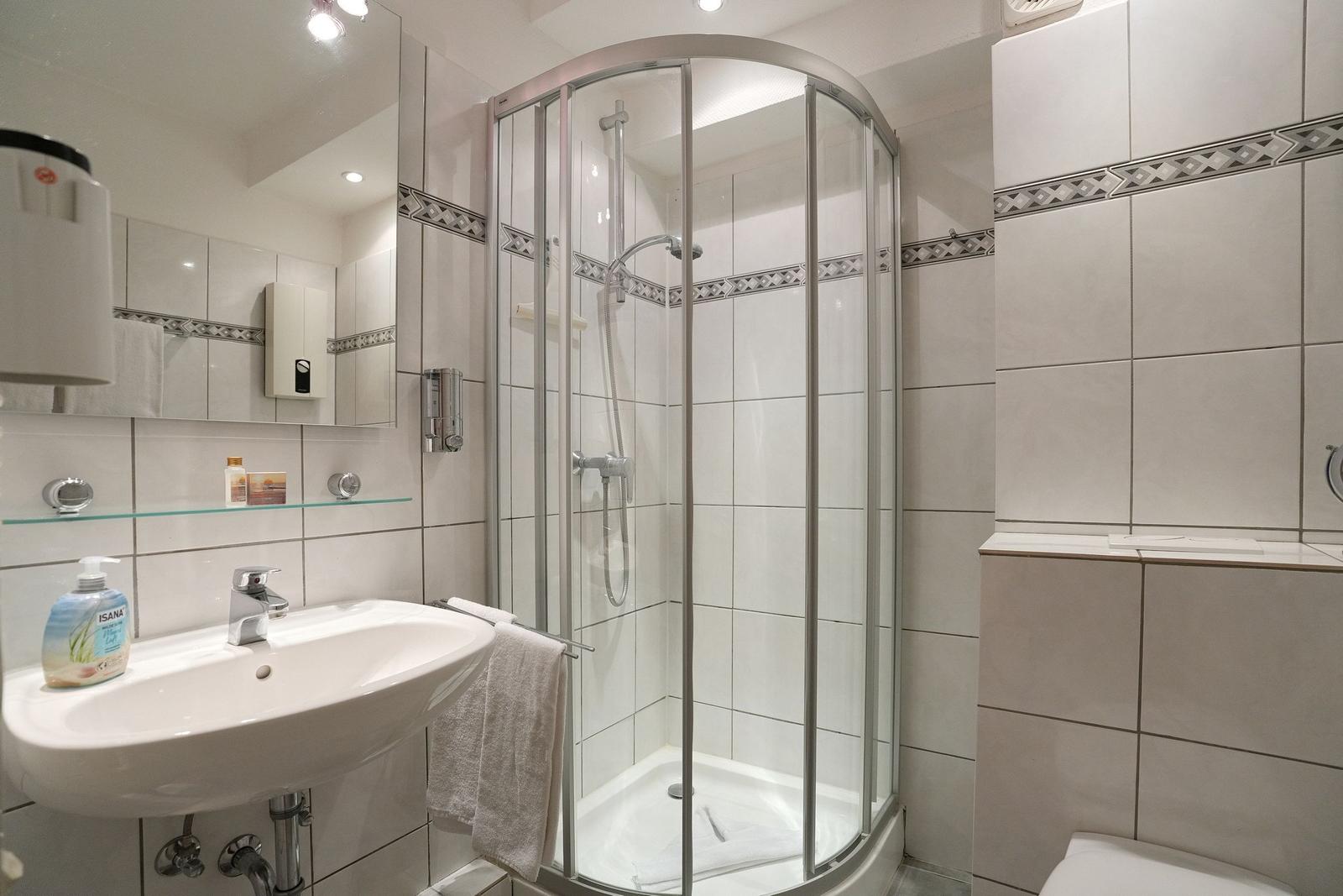 Badezimmer mit Dusche, Waschbecken und Toilette.