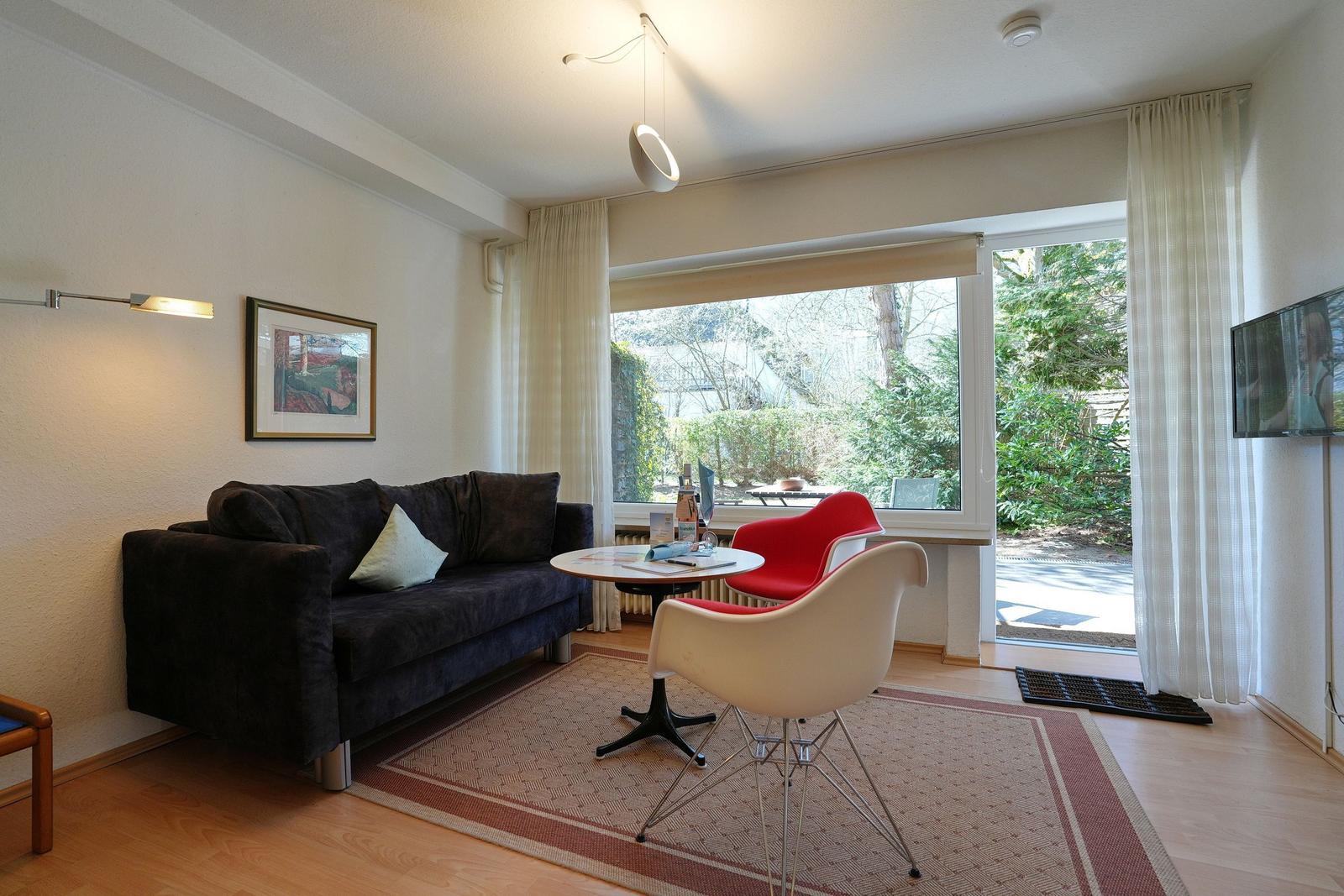Ein Wohnzimmer mit Sofa, zwei Stühlen und einem Fernseher an der Wand.