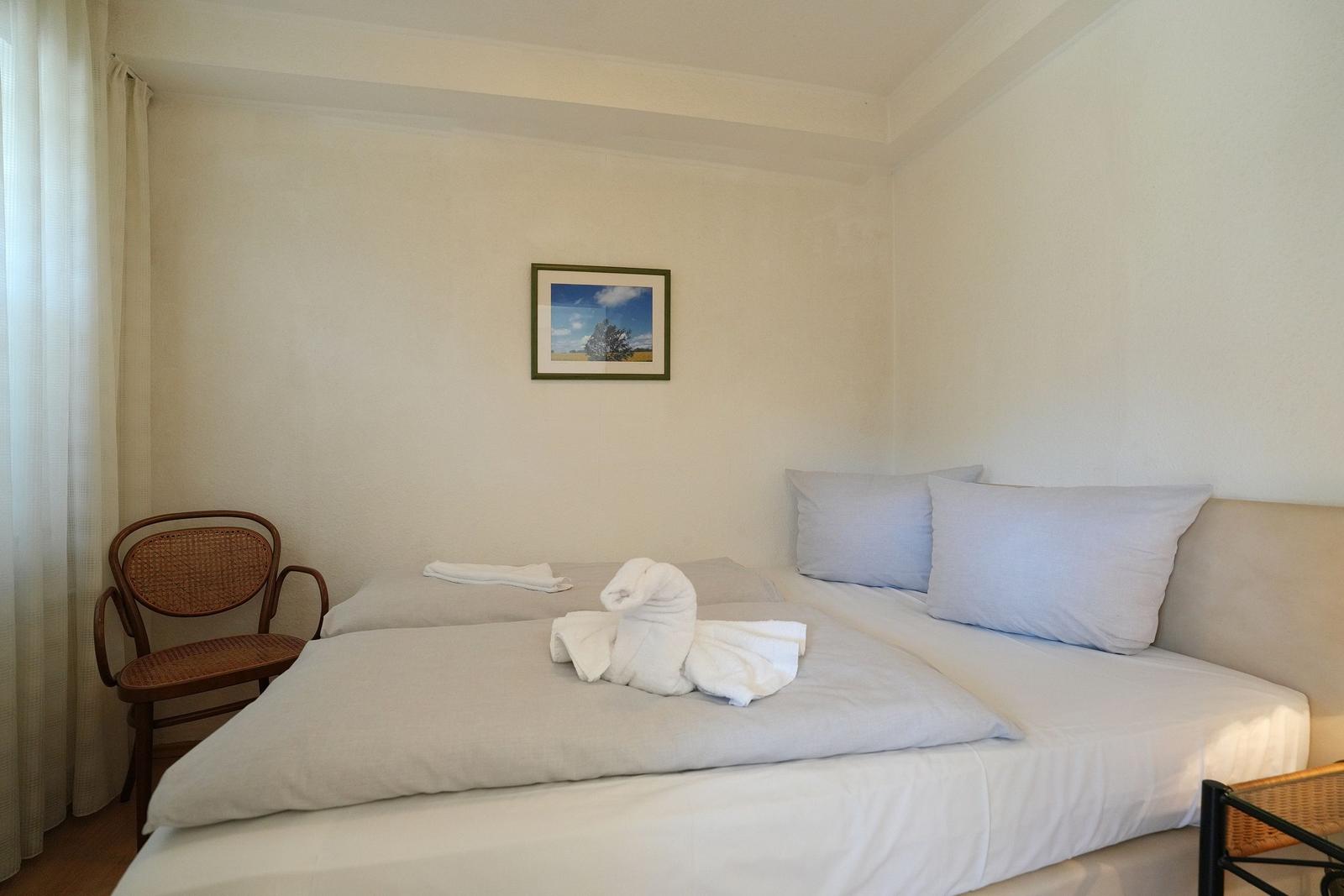 Schlafzimmer mit Bett, Stuhl und Wandbild