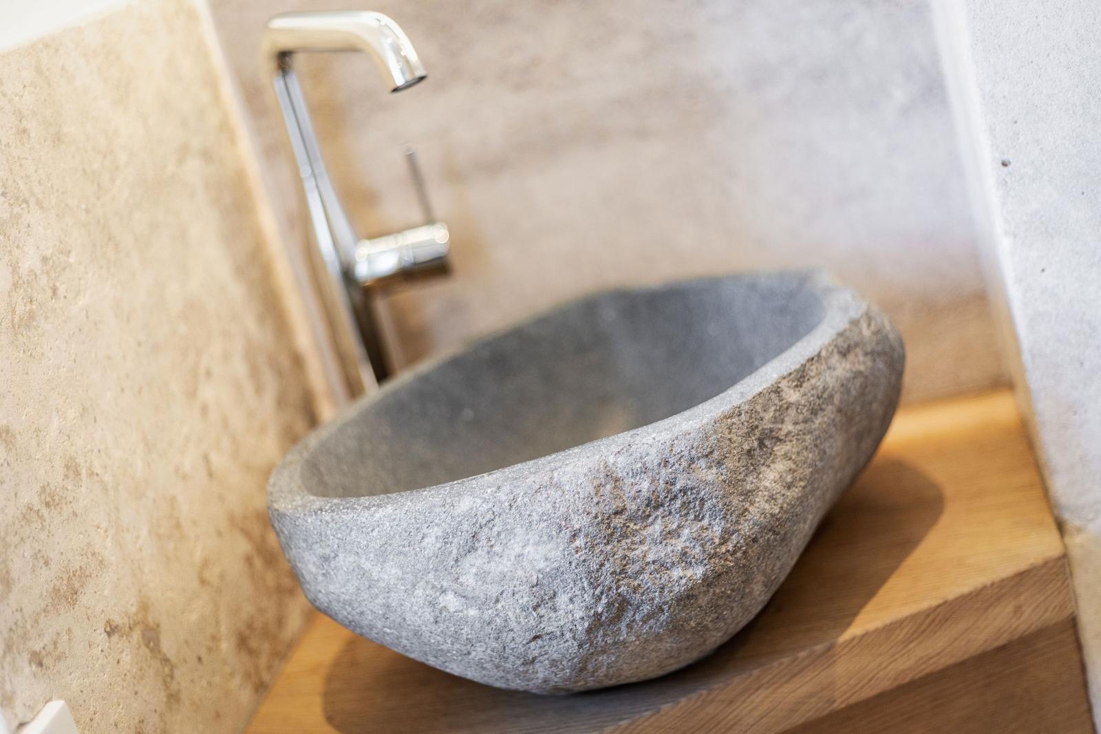 Stone sink on wooden base with modern faucet
