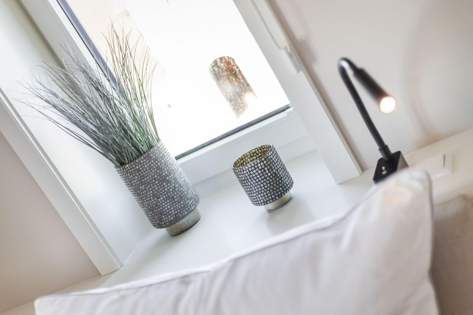 A windowsill with a plant, cup, and a lamp.