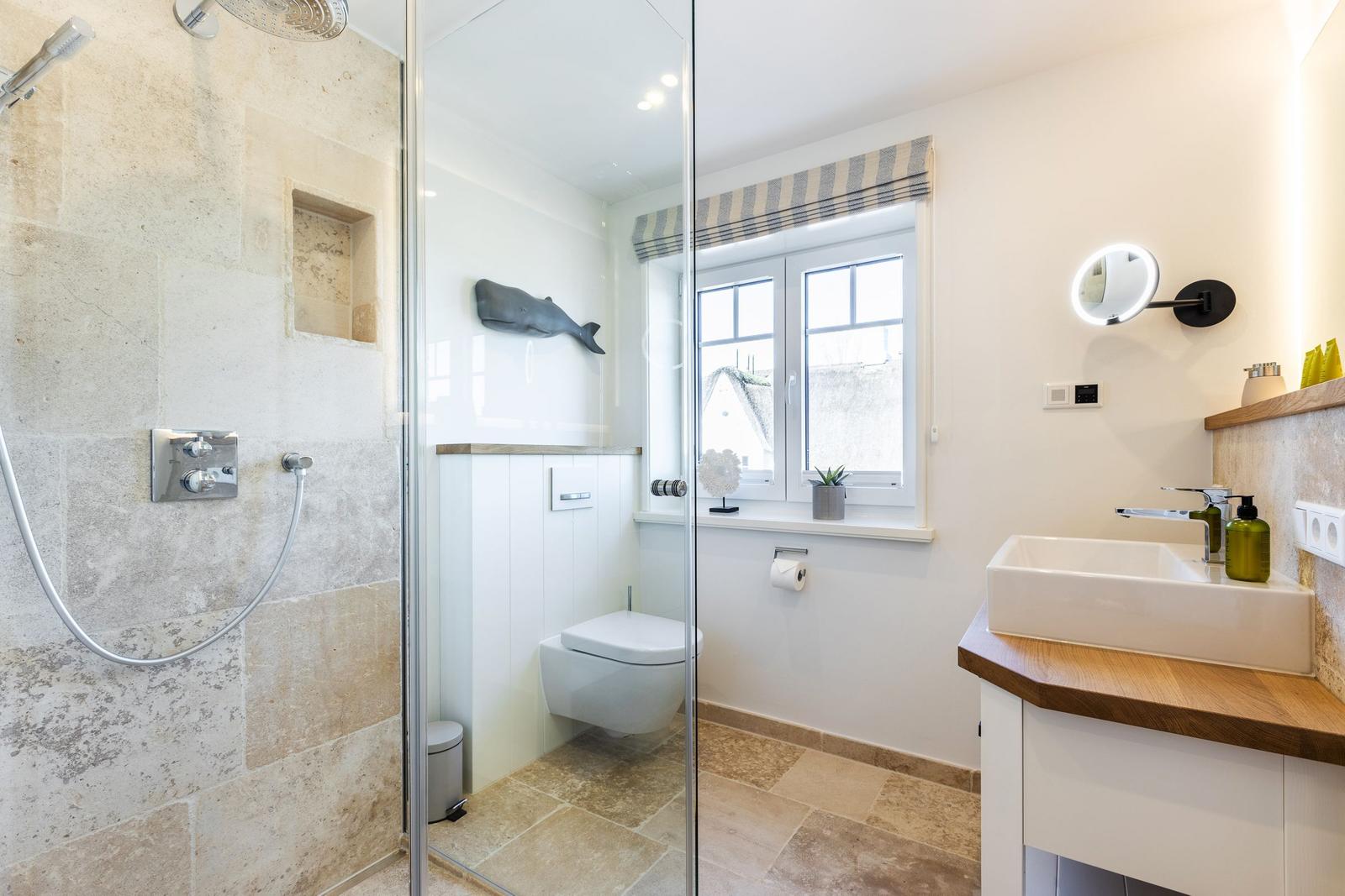 Bathroom with shower, toilet, and sink with wooden countertop.