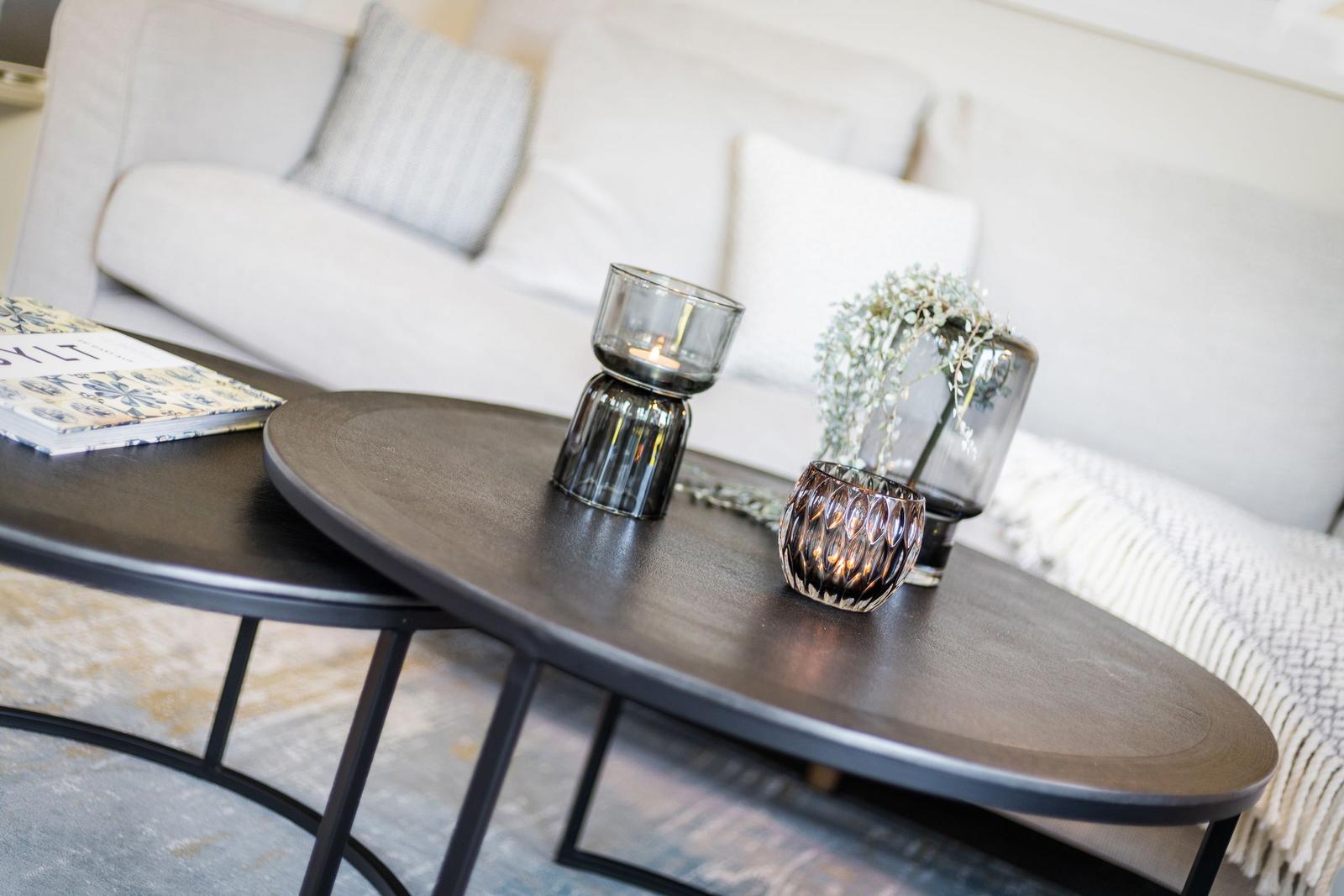 Round table with glass containers and book in front of sofa