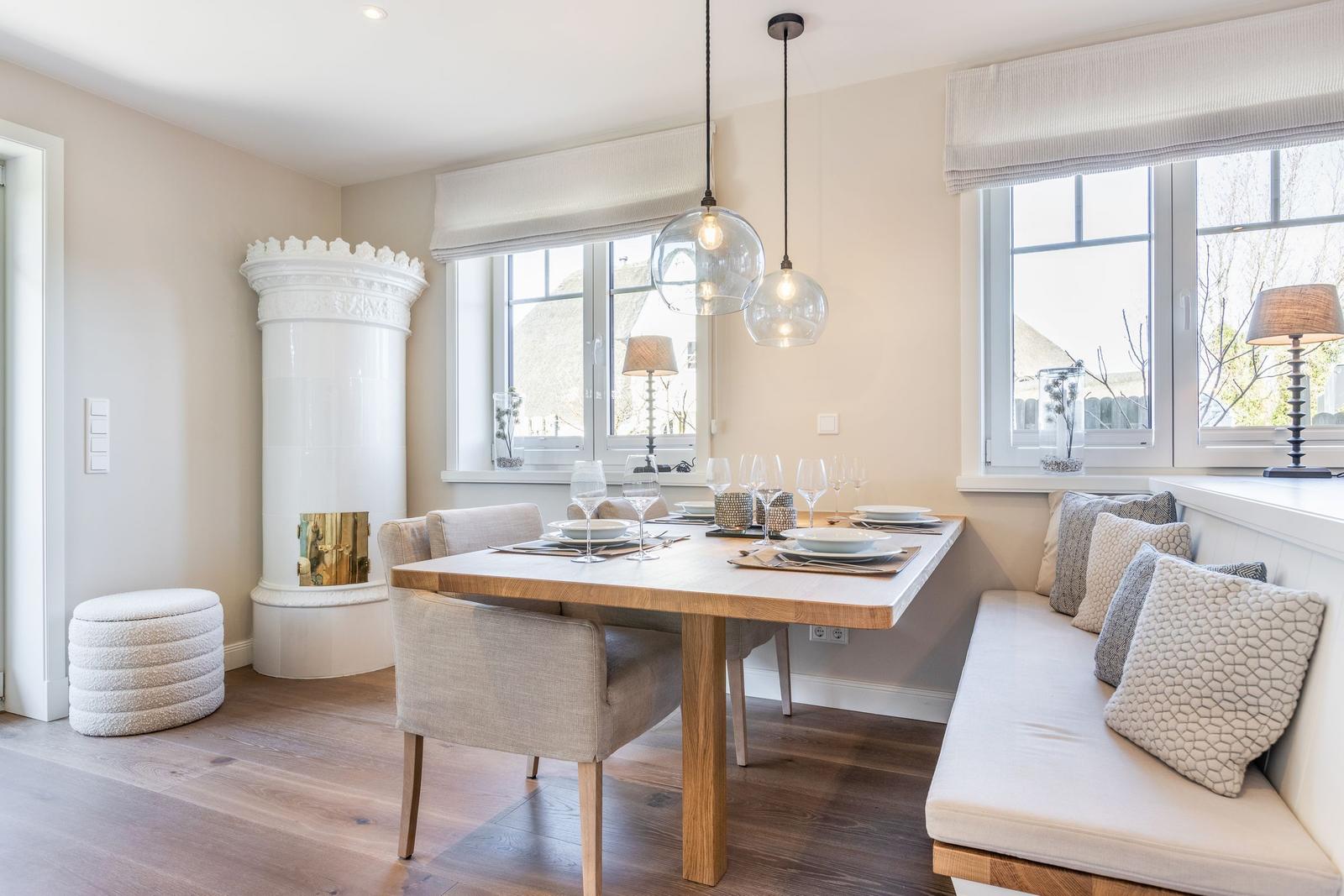 Dining room with wooden table, bench, and white windows.