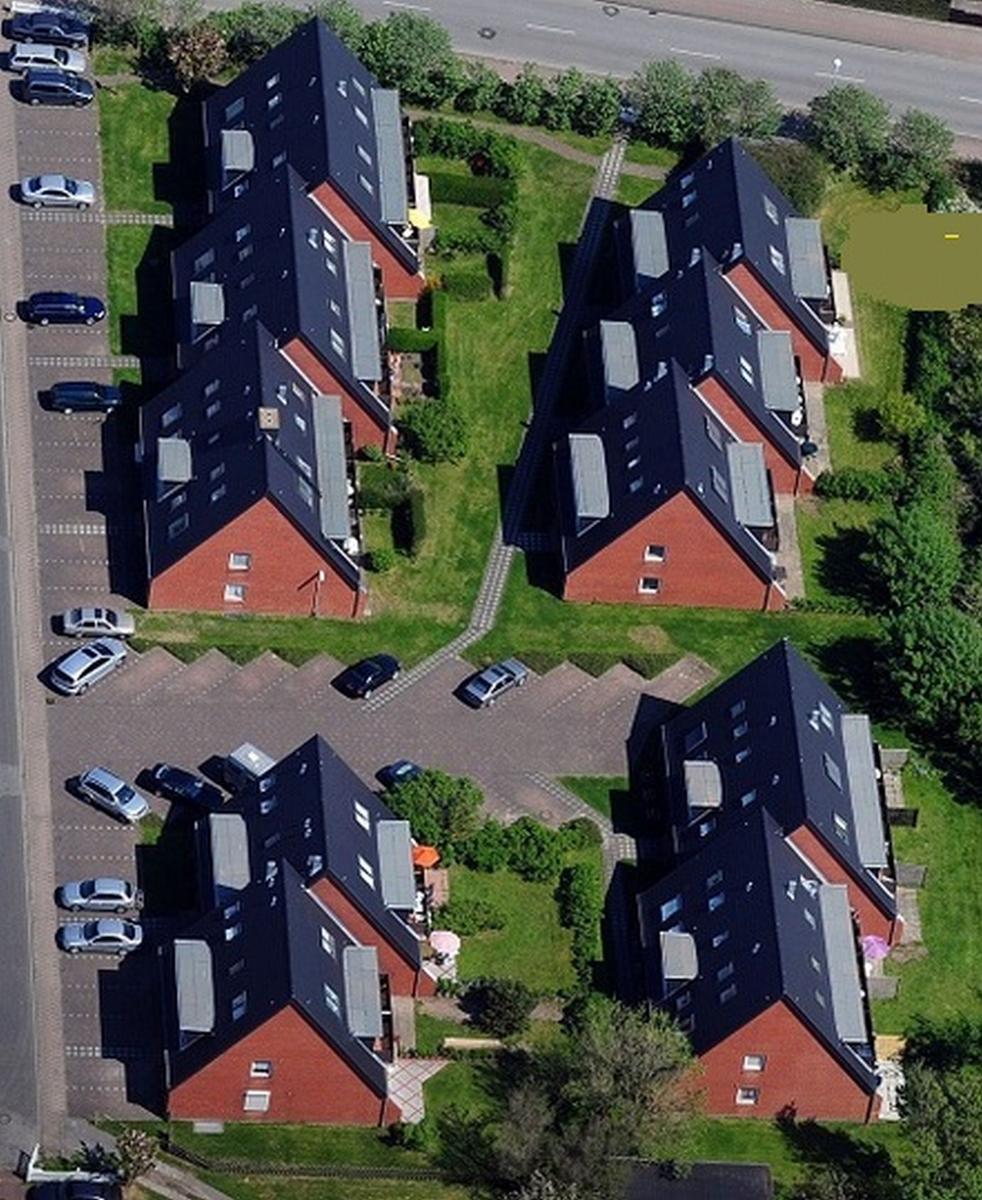 Luftbild von vier modernen Wohnhäusern mit Garten und Parkplatz.