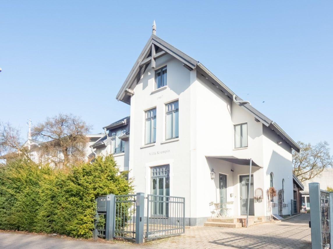 Weißes Haus mit Gartentor und Schild Villa Krempin. Fenster und Dach sichtbar.
