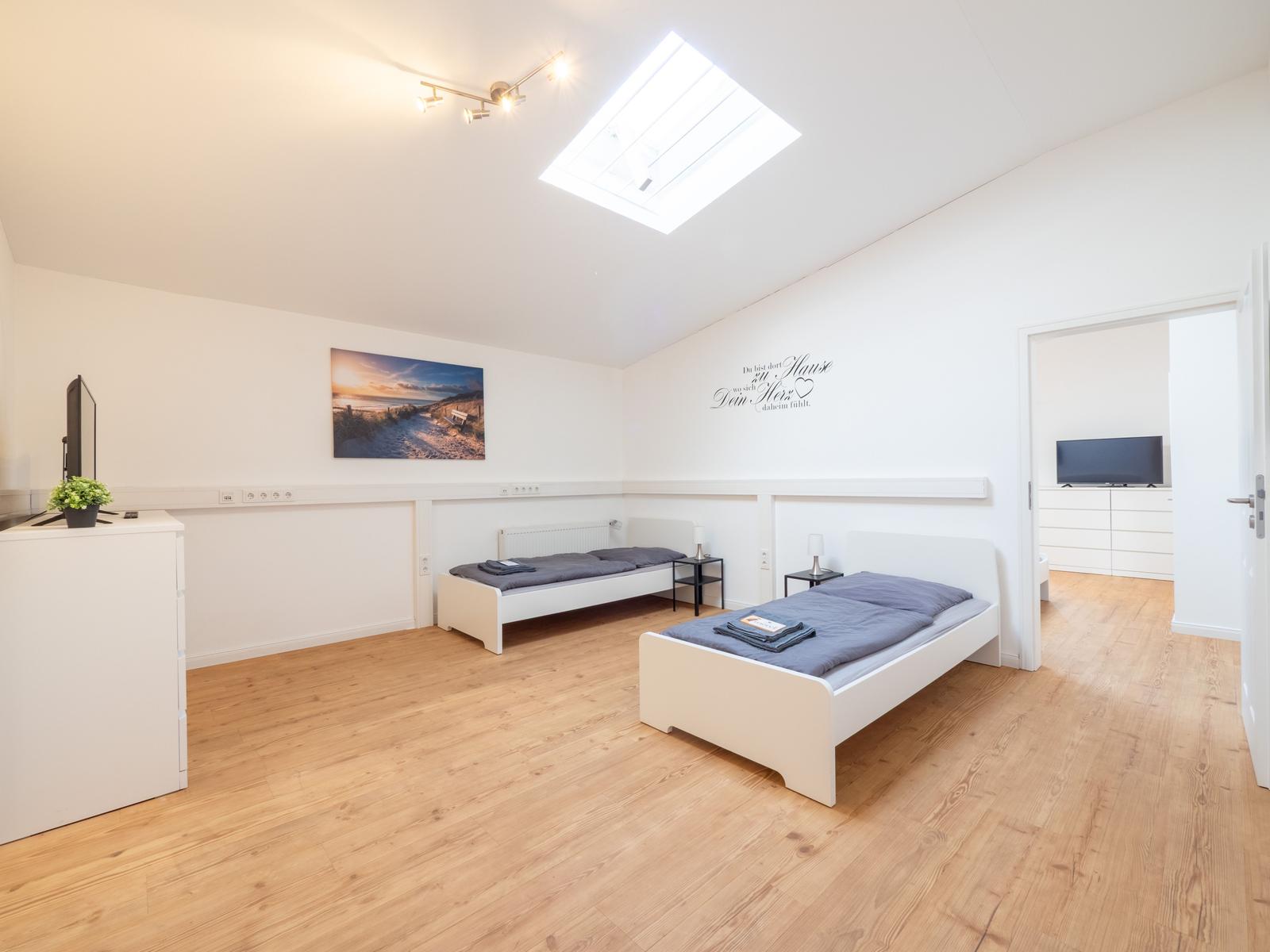 Zwei Betten, Holzboden, Dachfenster und Fernseher in einem Schlafzimmer.