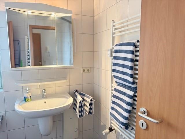 Badezimmer mit Waschbecken, Spiegel und Handtüchern auf Heizung
