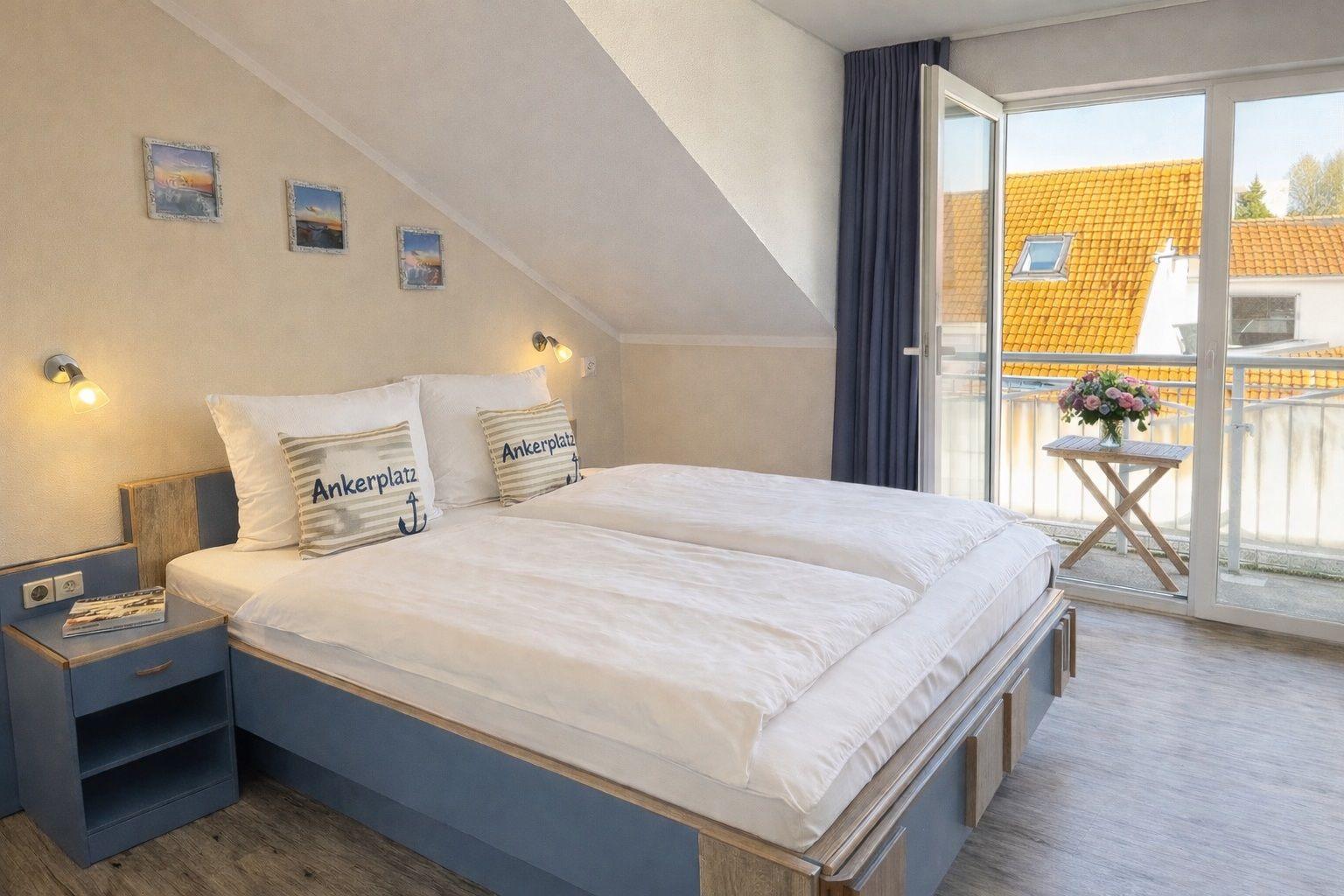 Schlafzimmer mit Dachschrägen, Bett mit Ankern, Nachttische und Balkonansicht.