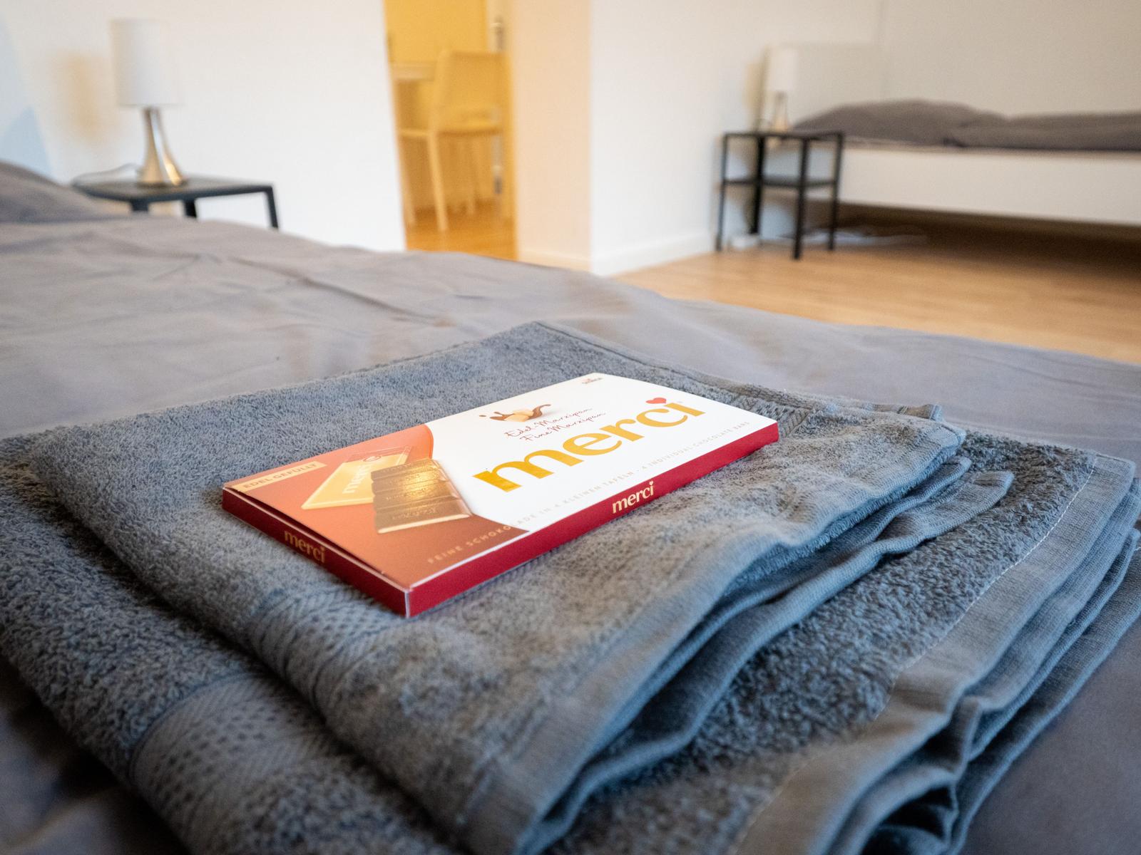 Ein Bett mit gefalteten Handtüchern und einer Schokoladentüte.