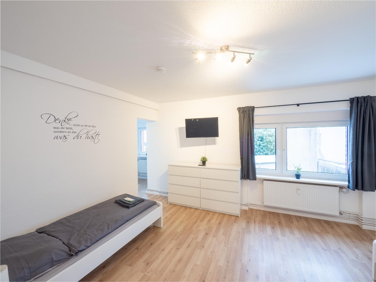 Schlafzimmer mit Bett, Schrank und Fenster. Wanddekoration und Holzboden.