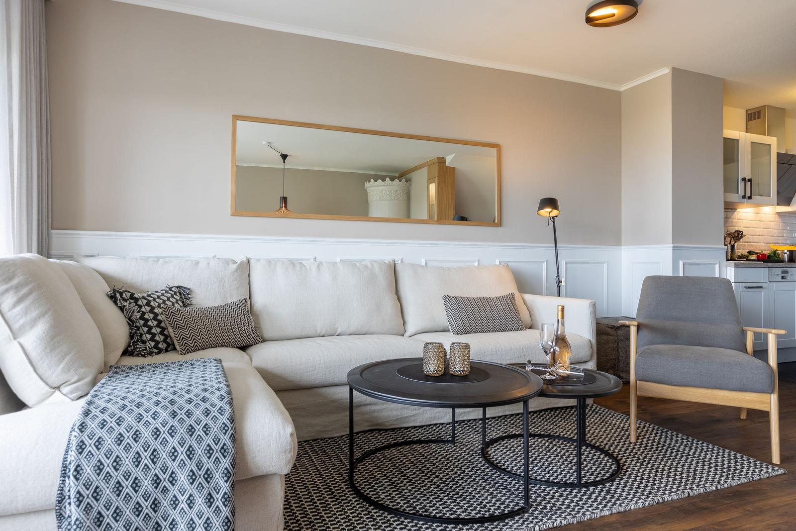 Wohnzimmer mit Sofa, Sessel und runden Tischen auf Teppich