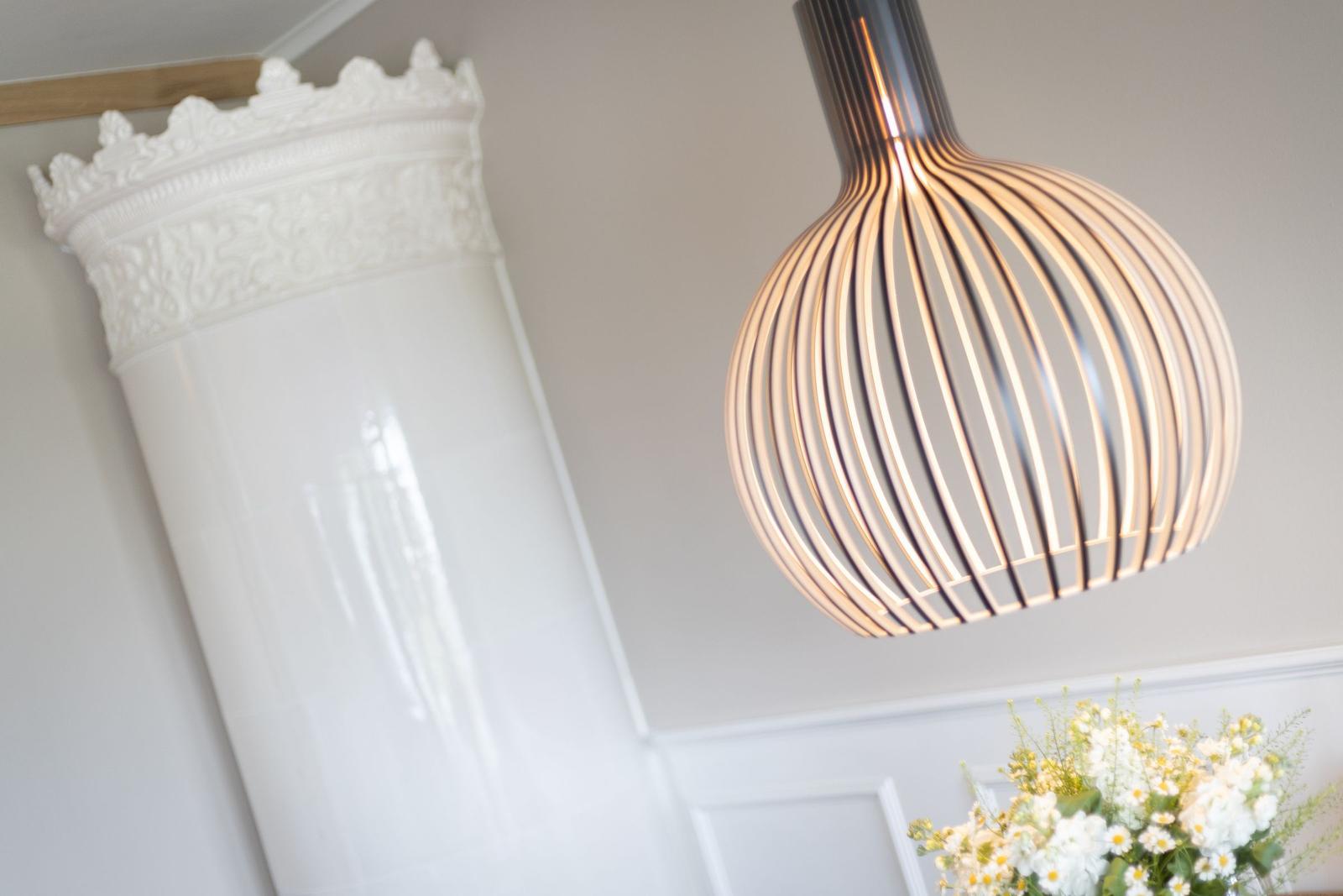 Deckenleuchte über Tisch mit Blumen und Säule