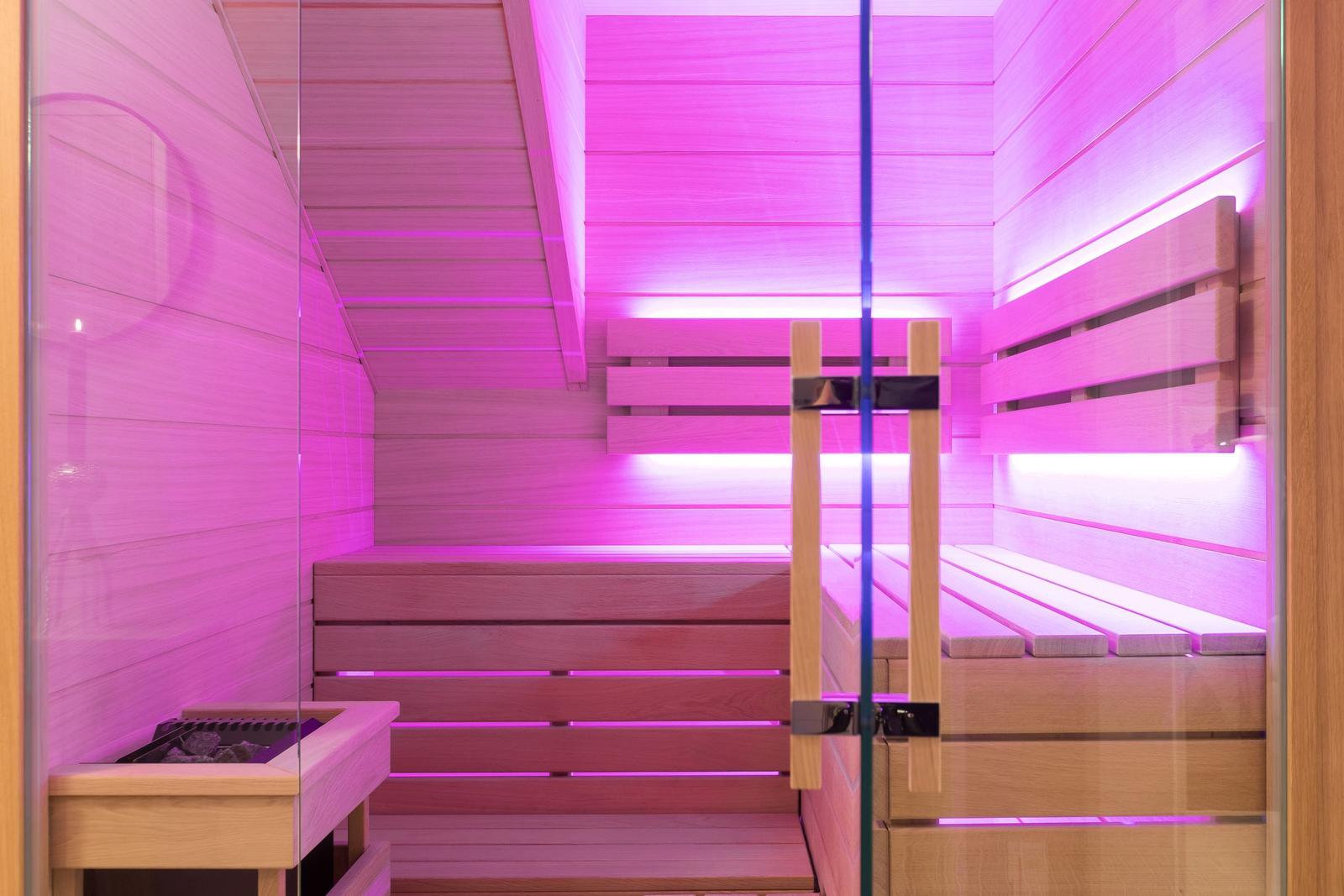 Sauna mit Holzbank und pinker Beleuchtung