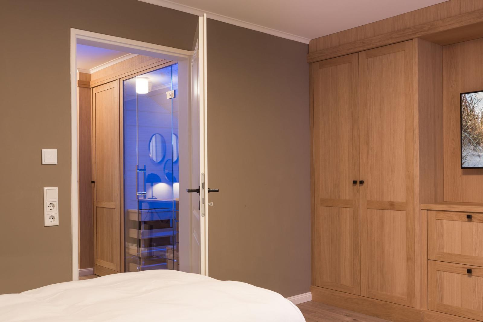 Schlafzimmer mit Blick in das Badezimmer und Holzschrank.