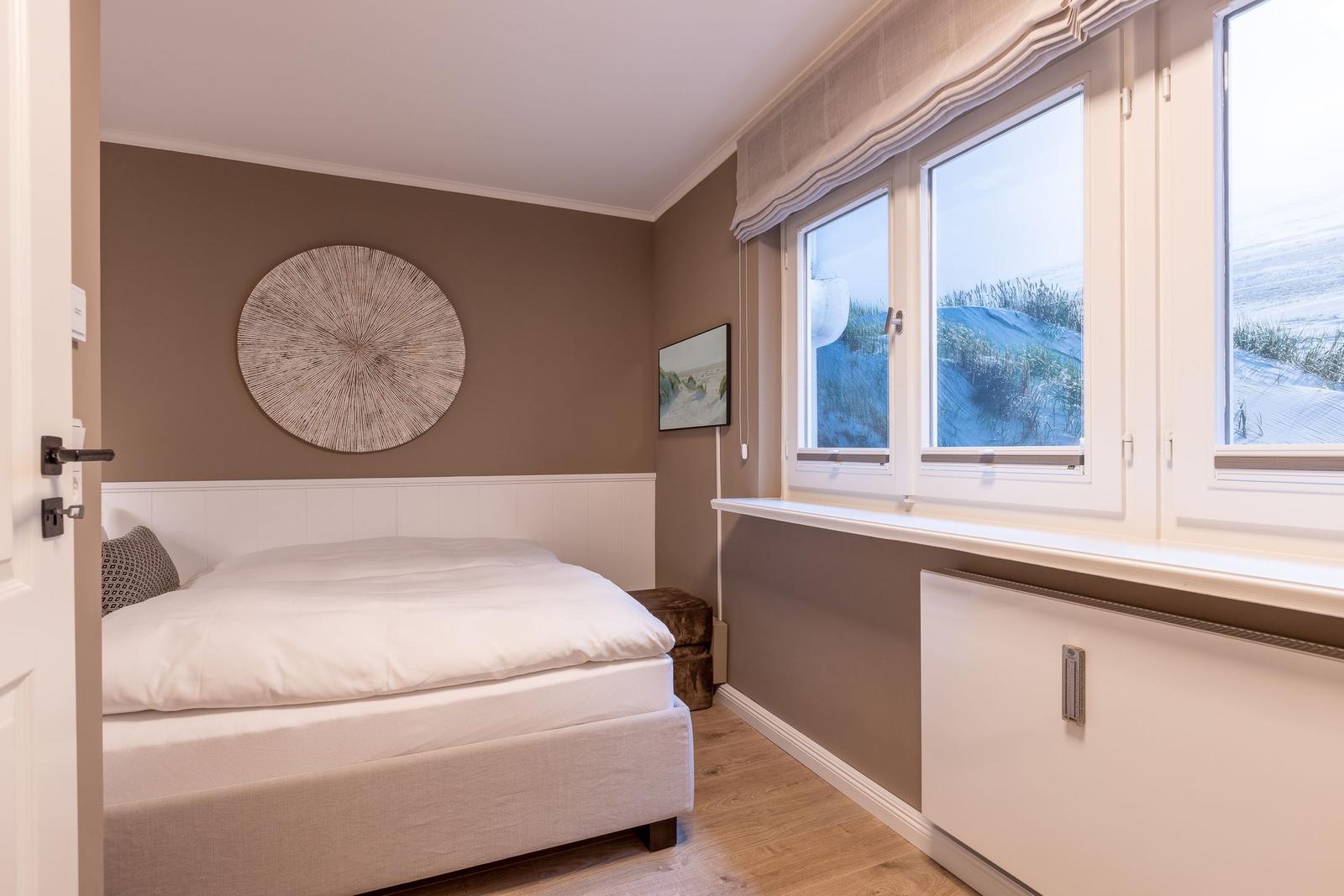 Schlafzimmer mit Bett, Fenster und Wanddekoration.