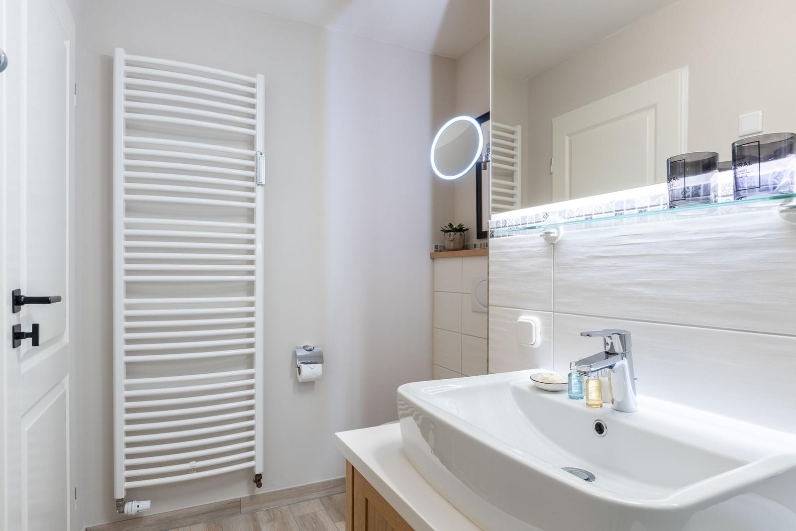 Badezimmer mit Waschbecken, Spiegel und Heizkörper