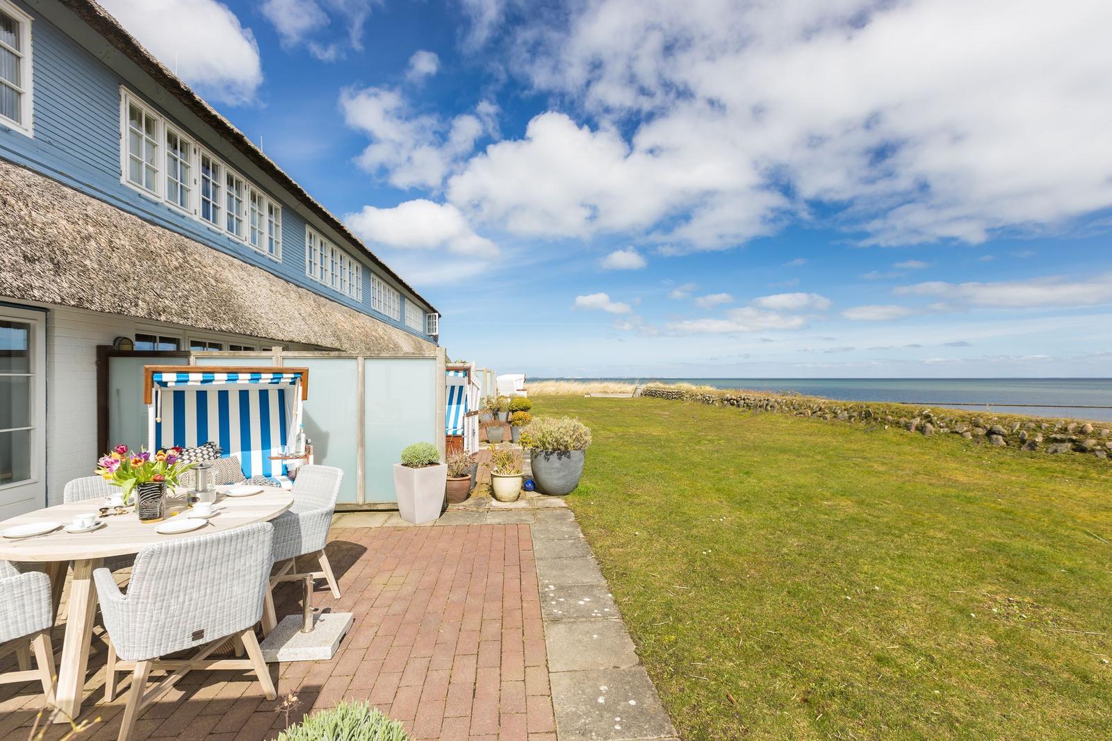Terrasse mit Tisch, Stühlen und Blick aufs Meer.