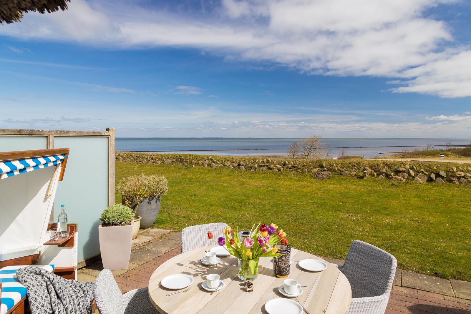 Terrasse mit Tisch, Stühlen und Blick auf das Meer.