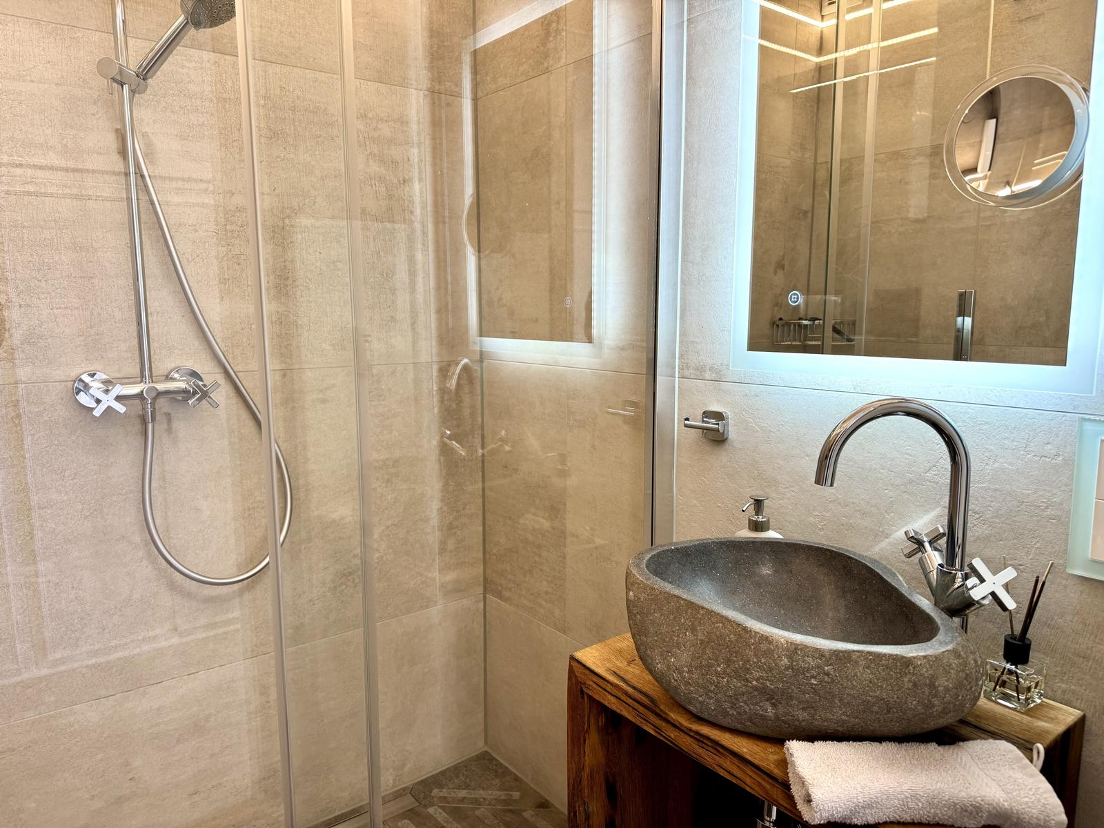 Bad mit Dusche, Steinwaschbecken und Spiegelschrank.