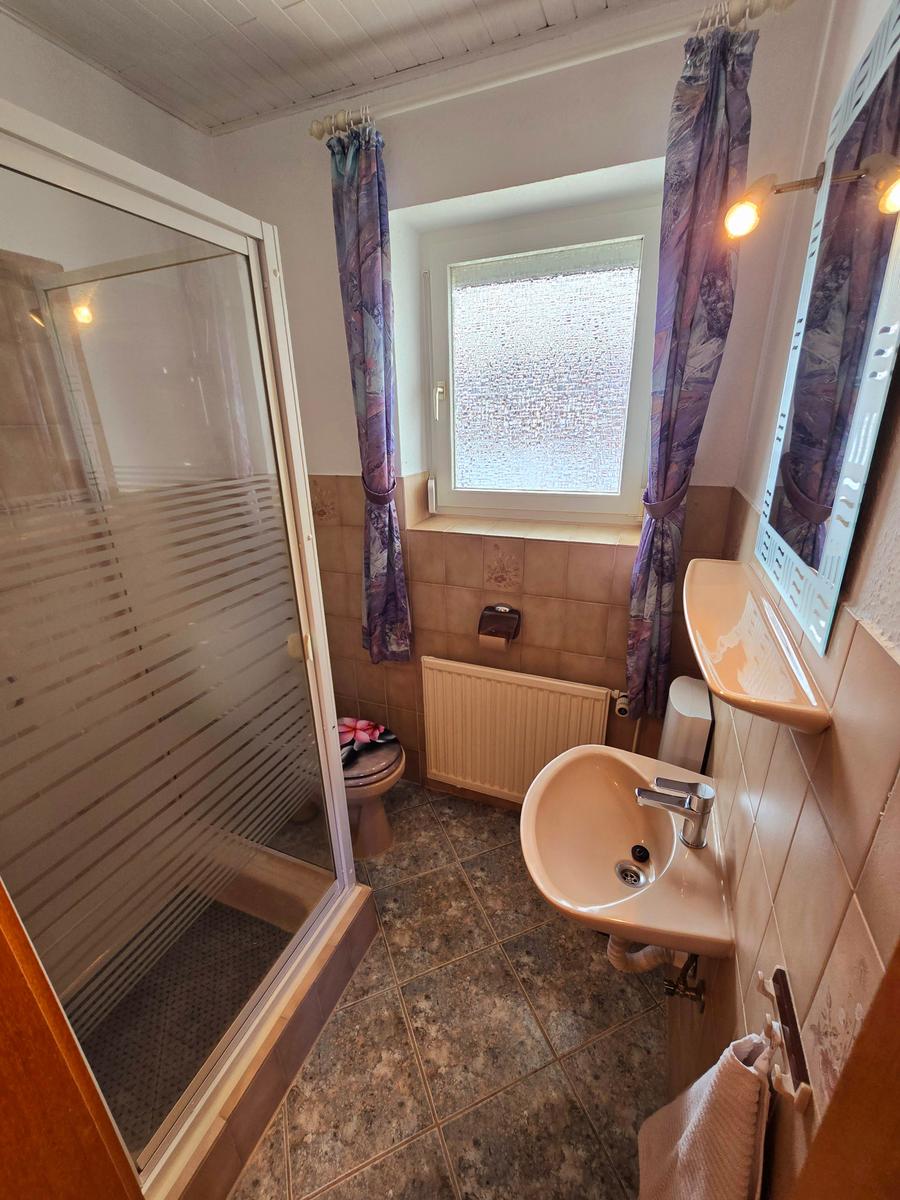 Badezimmer mit Dusche, Waschbecken und funktionaler Ausstattung.