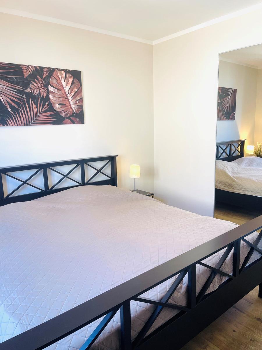 Schlafzimmer mit Bett, Wandbild und Spiegel