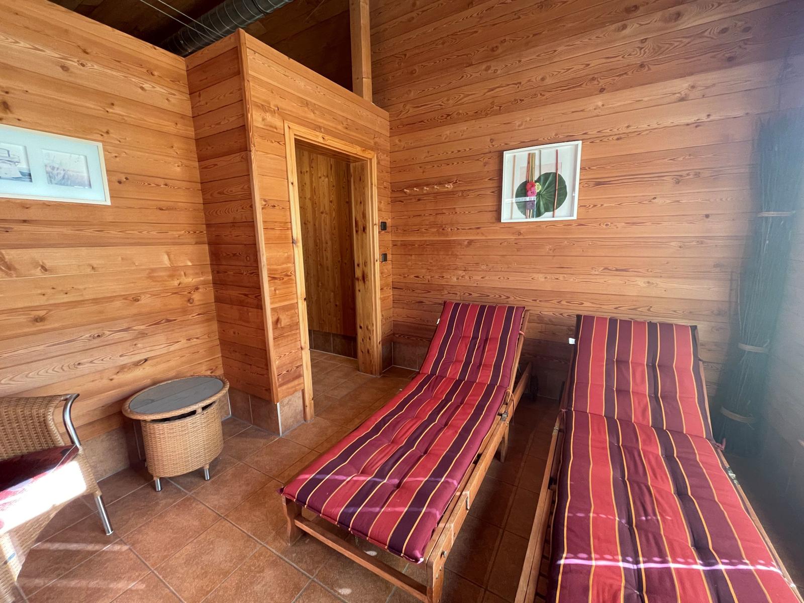 Zwei Liegestühle mit Streifenkissen, Holzwände und Tür im Hintergrund.