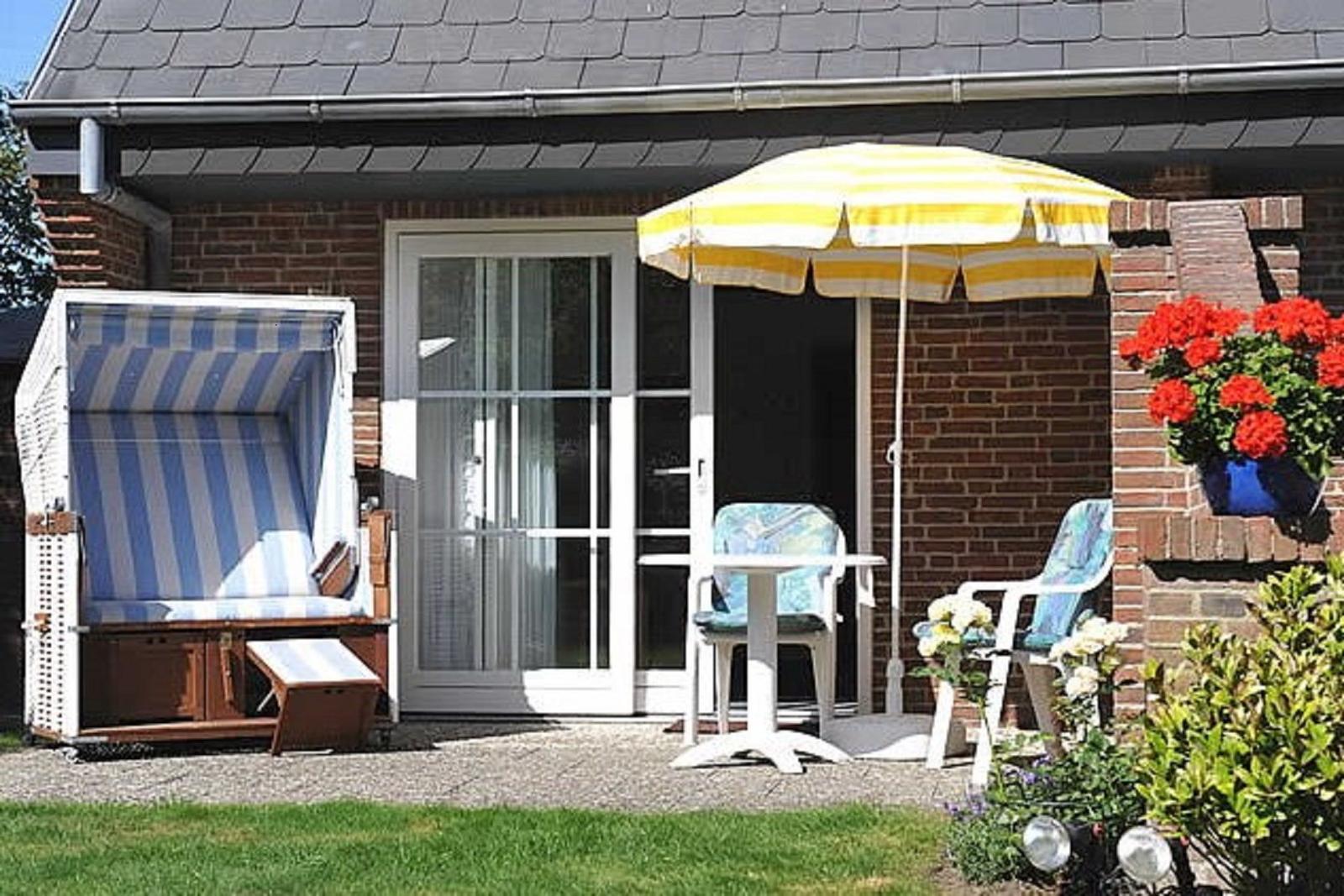 Terrasse mit Sonnenschirm, Stühlen und Strandkorb vor Haus