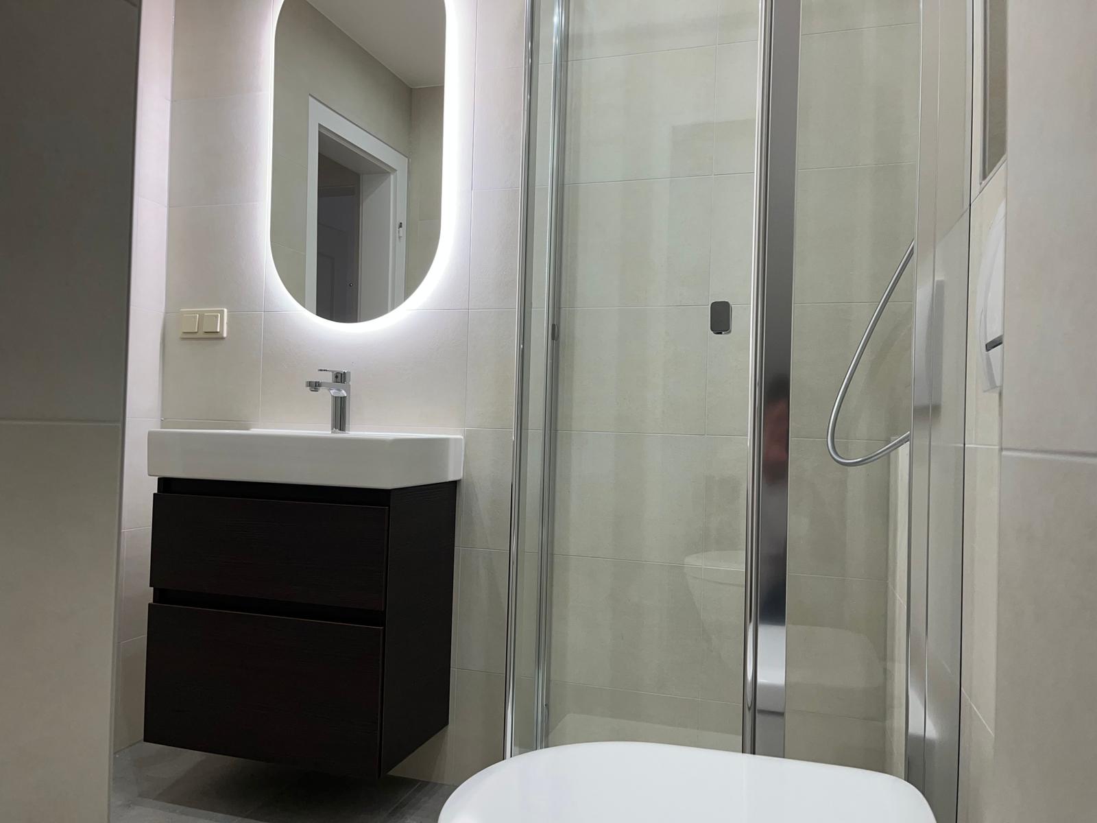 Badezimmer mit Dusche, Waschbecken und Spiegel