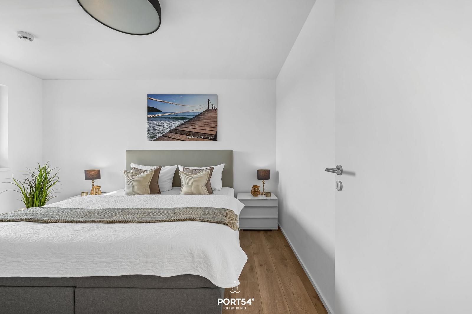 Schlafzimmer mit Bett, Nachttischen und Wandbild an der Wand.