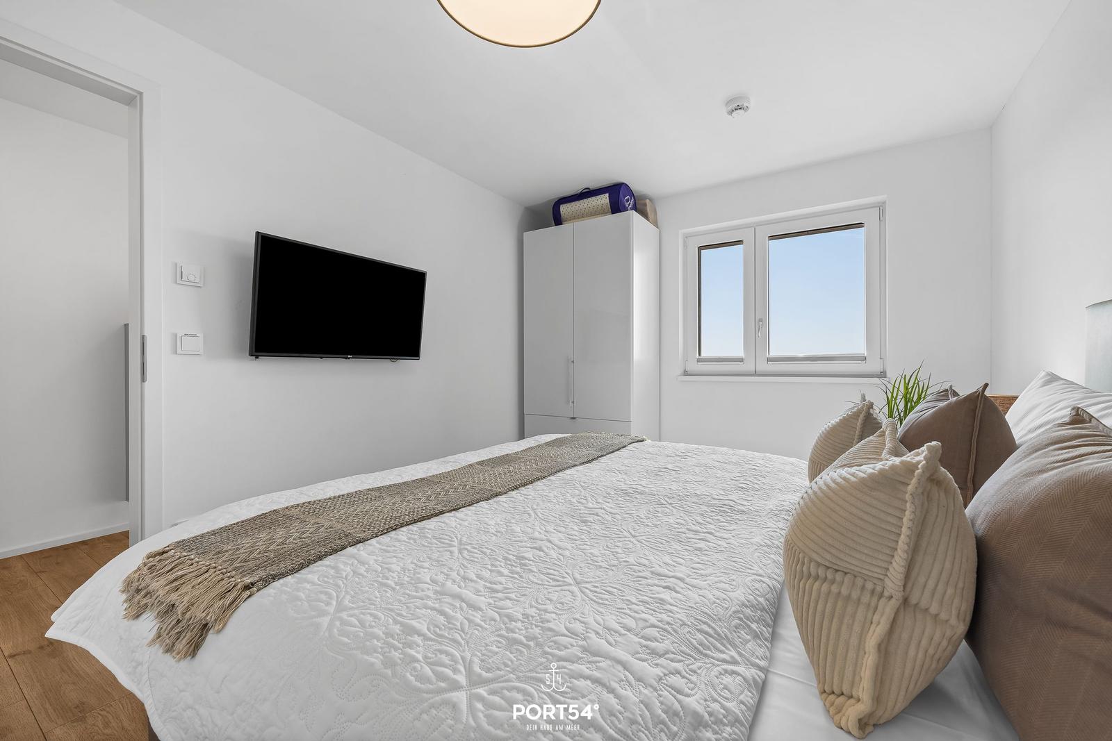 Schlafzimmer mit Bett, Fernseher und Fenster