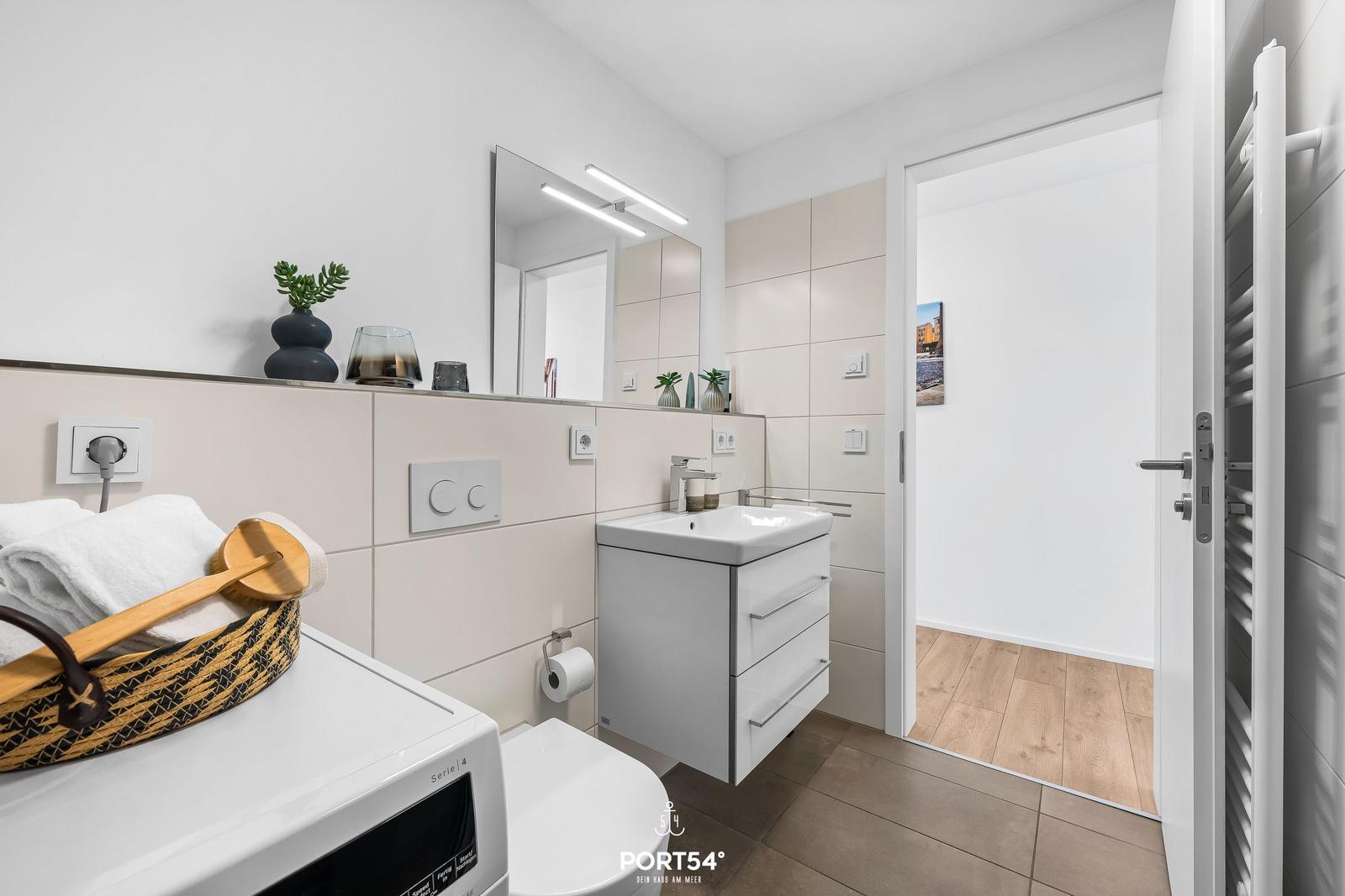 Badezimmer mit Waschbecken, Spiegel, Toilette und Wärmekörper