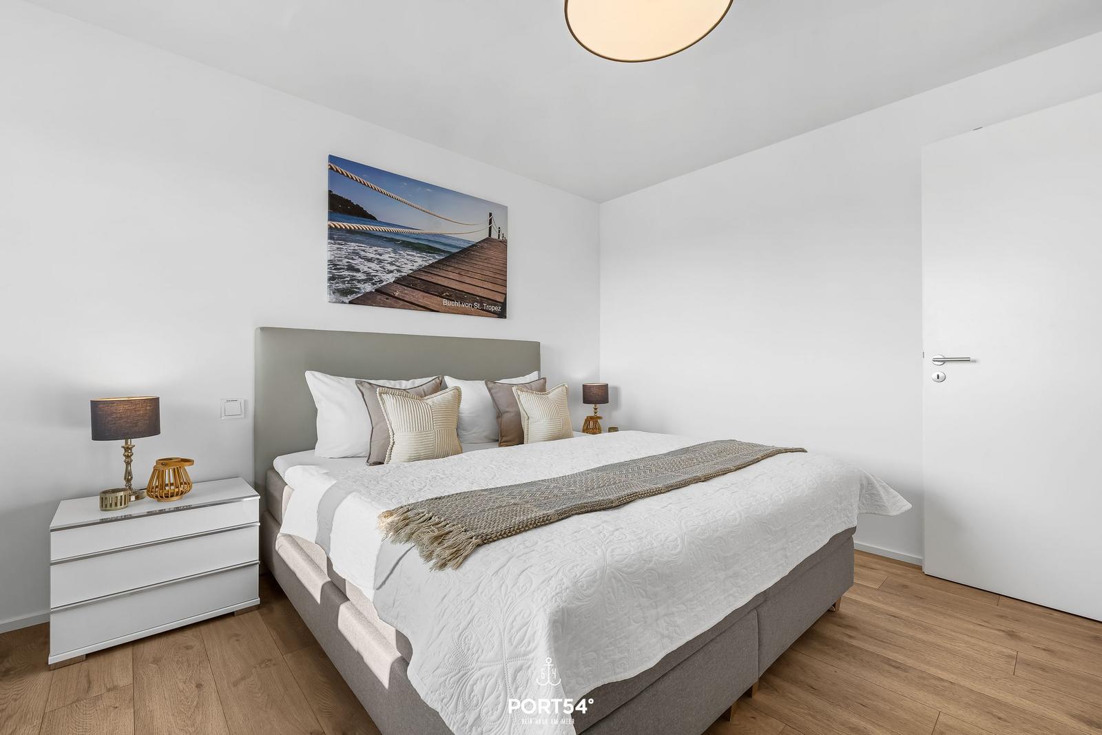 Schlafzimmer mit Bett, Nachttisch und Wandbild an der Wand.