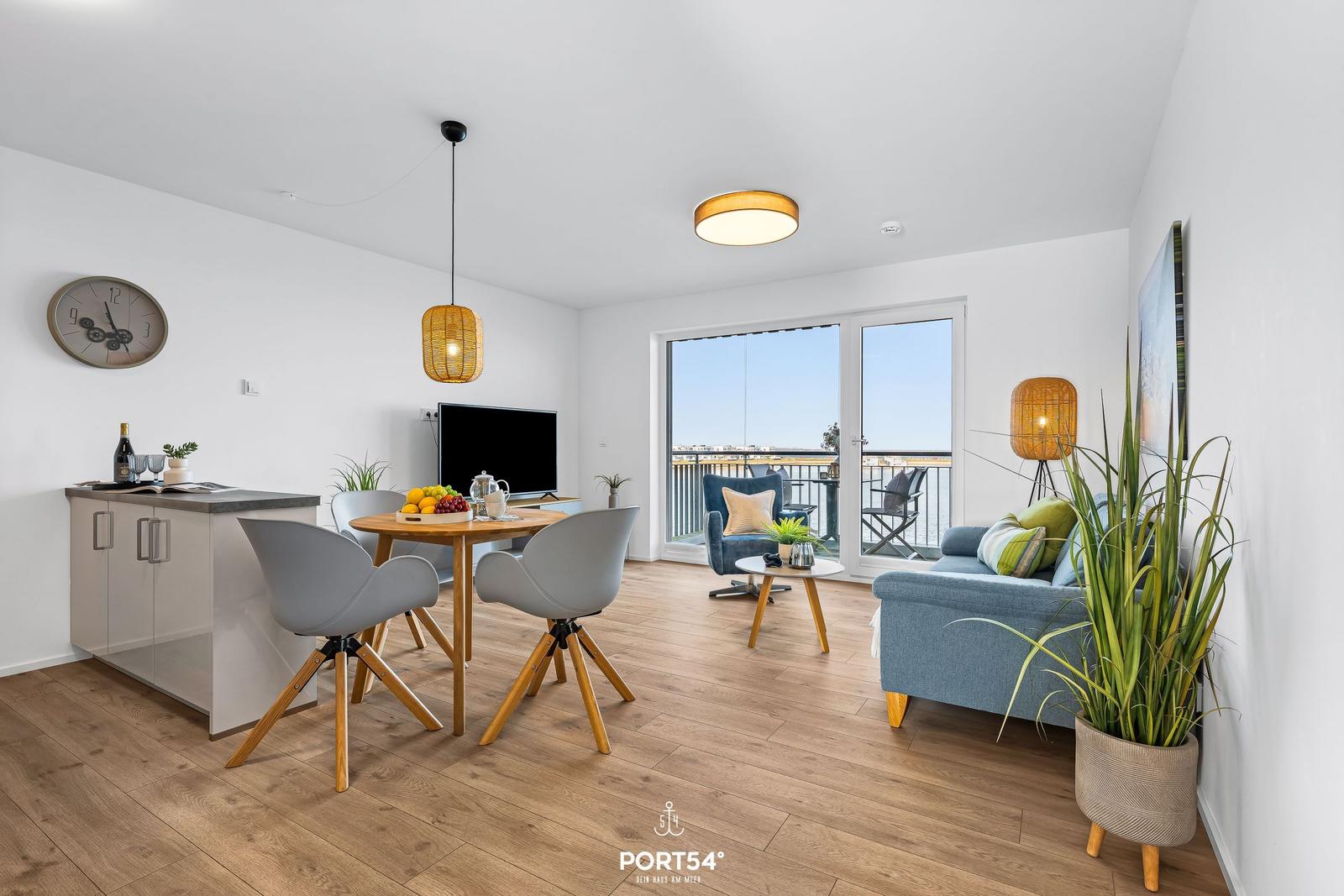 Wohnung mit Essbereich, Sofa und Balkon. Holzboden, weiße Wände und moderne Einrichtung.