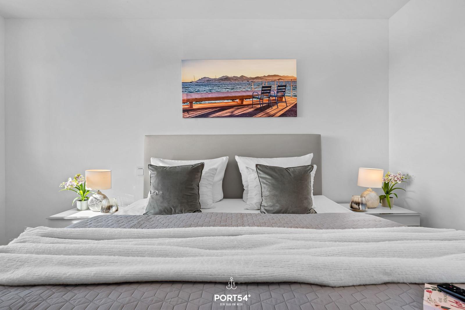 Schlafzimmer mit Bett, Nachttischen und Wandbild an der Wand.