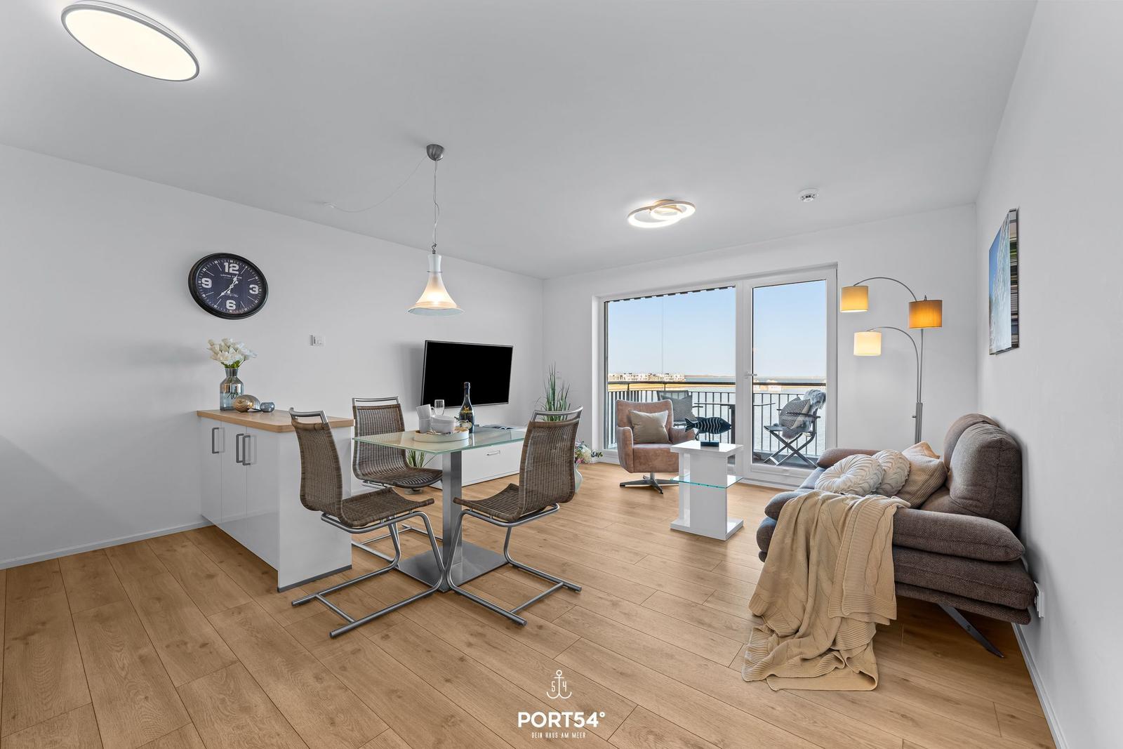 Wohn- und Essbereich mit Balkon, Sofa, Esstisch und Fernseher.