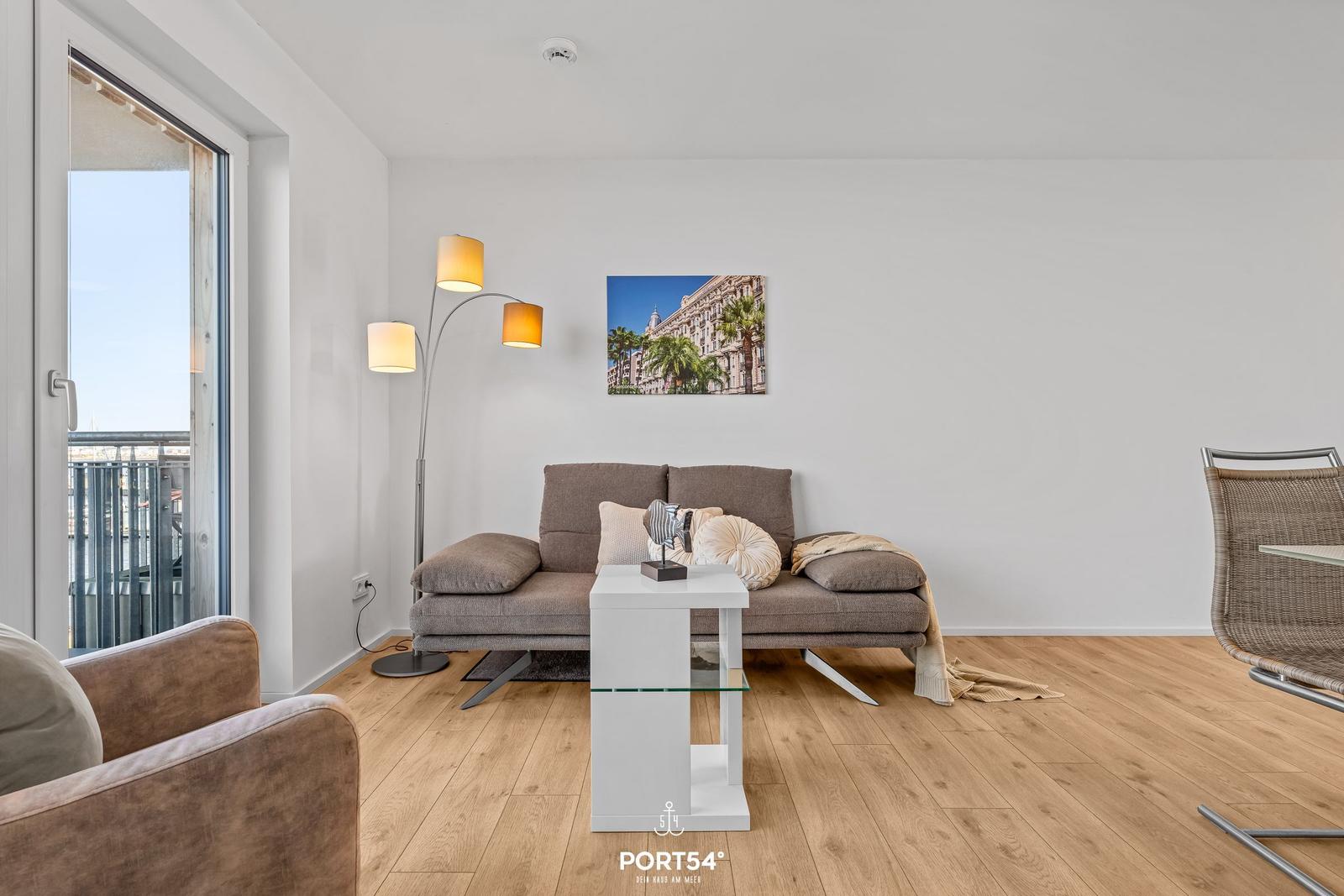 Wohnzimmer mit Sofa, Tisch und Balkonansicht.