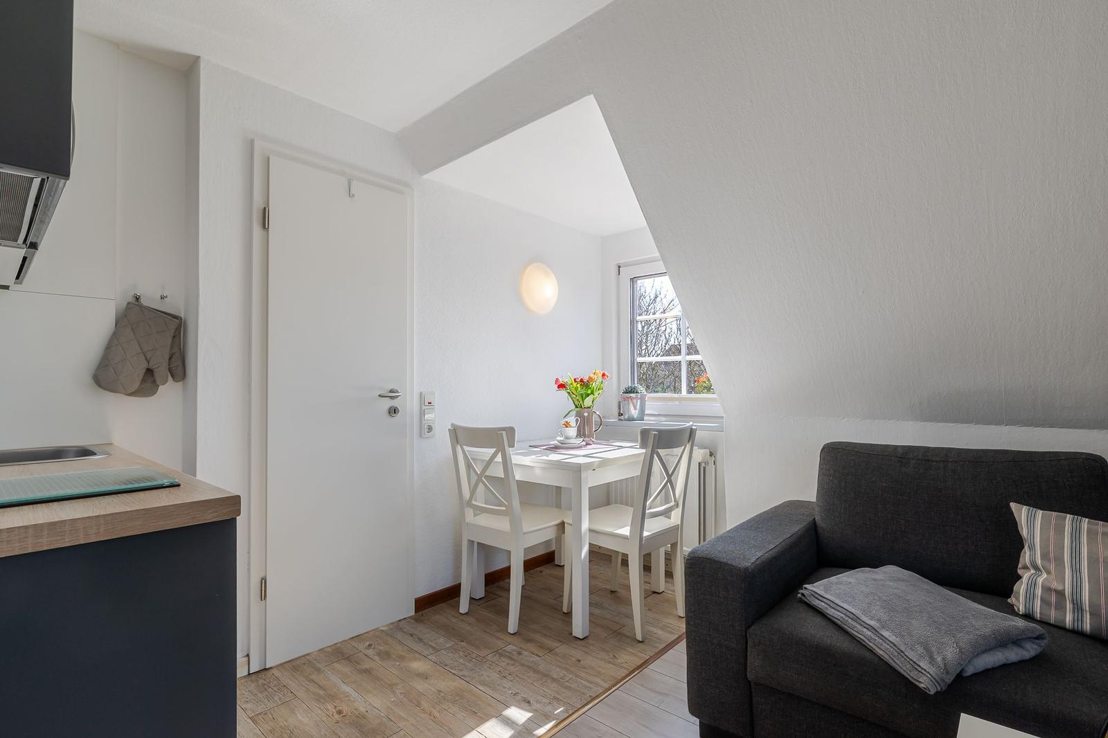 Wohnbereich mit Sofa, Esstisch und Küchenzeile unter Dachschrägen.